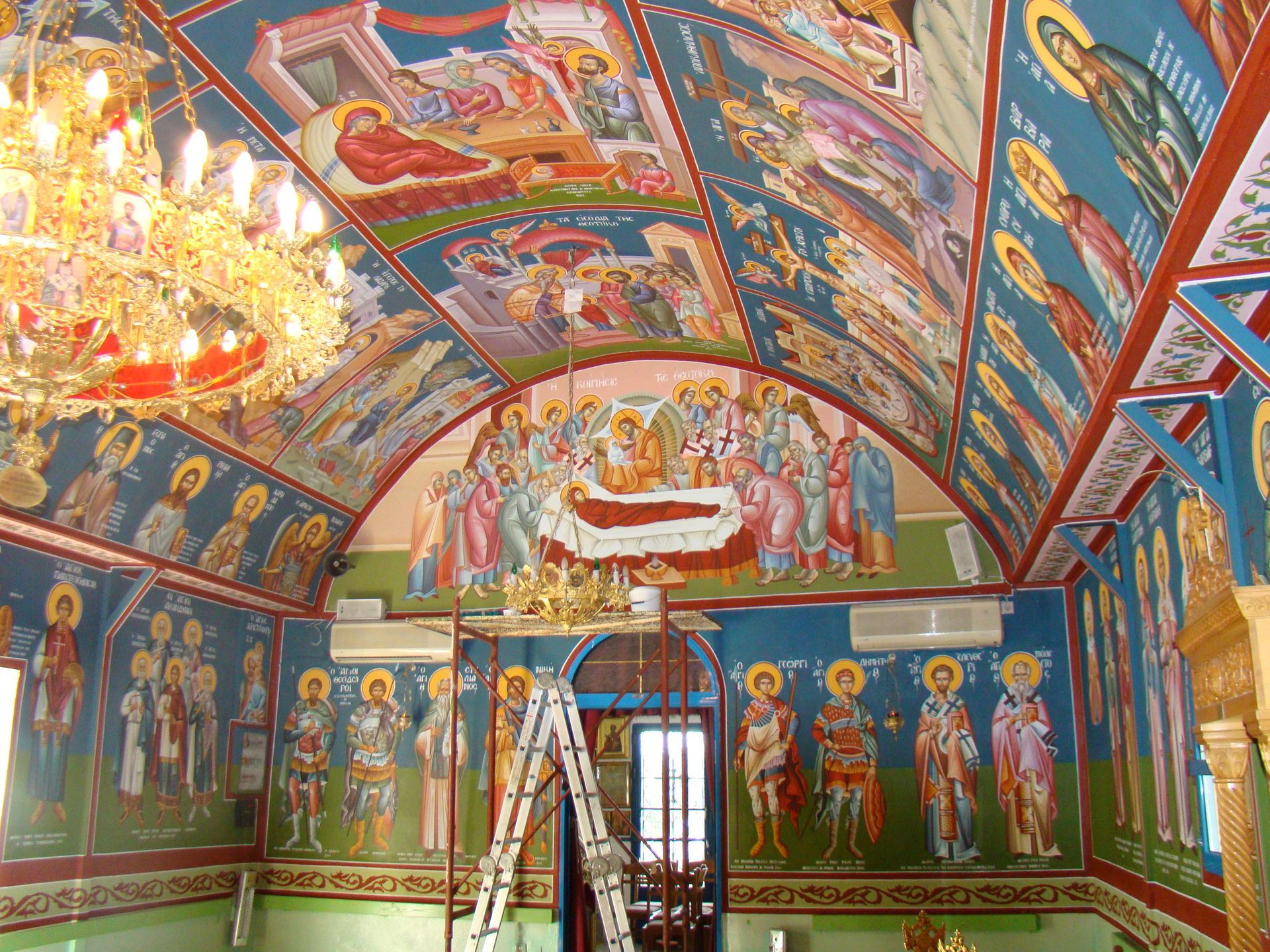 A ladder is sitting in front of a painting on the ceiling of a church.