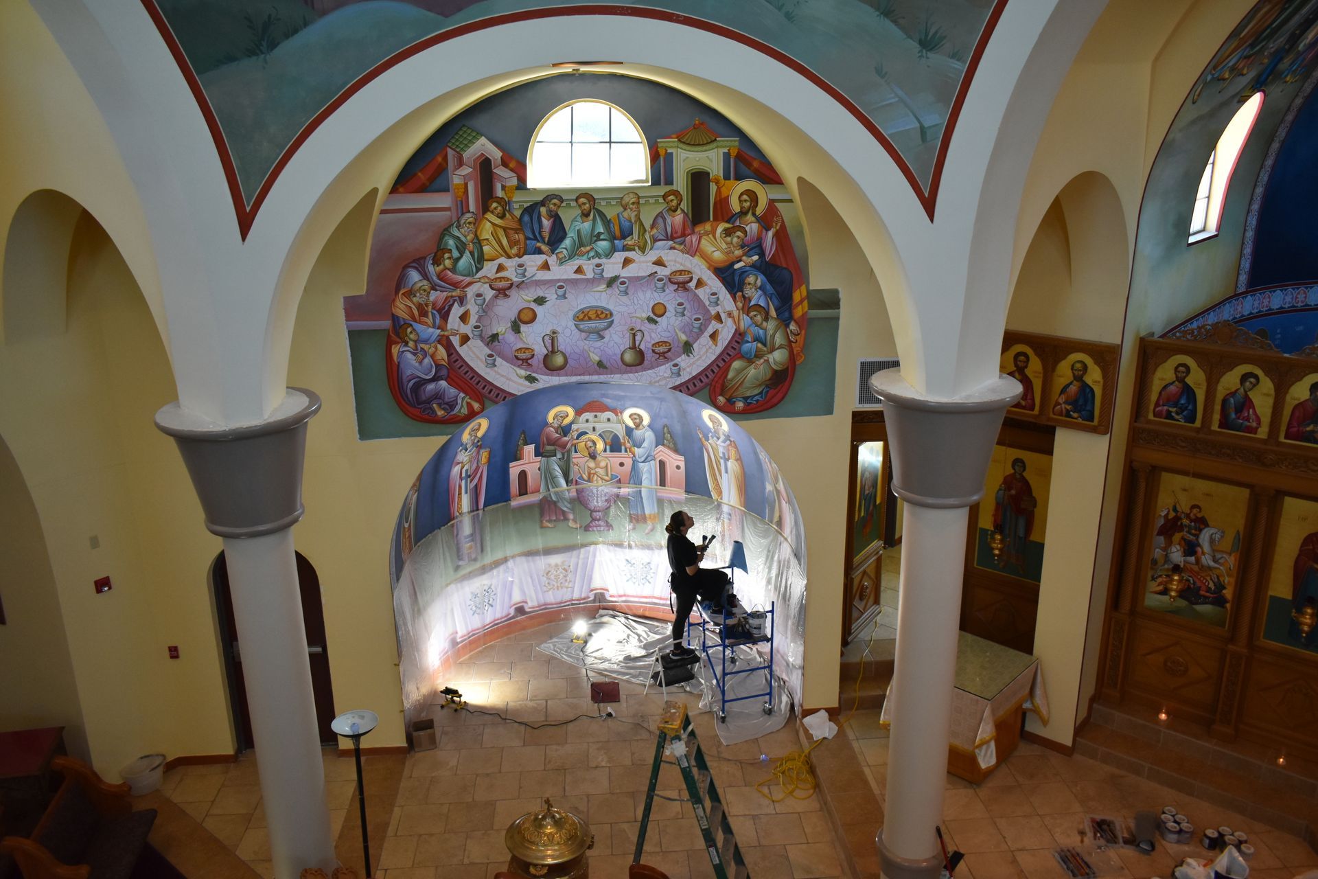 A man is painting a mural on the wall of a church