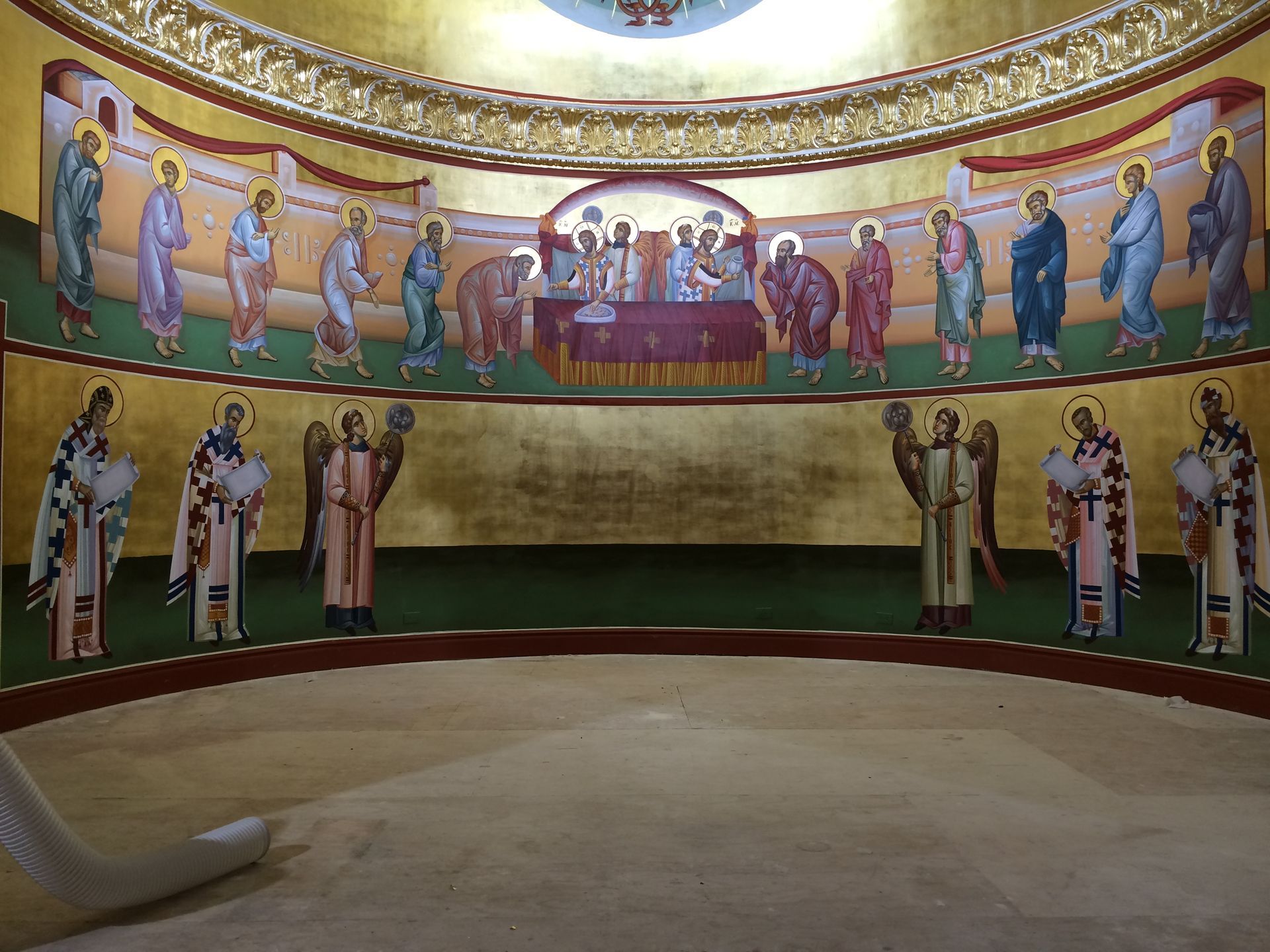 A painting of jesus and his apostles is on the wall of a church.