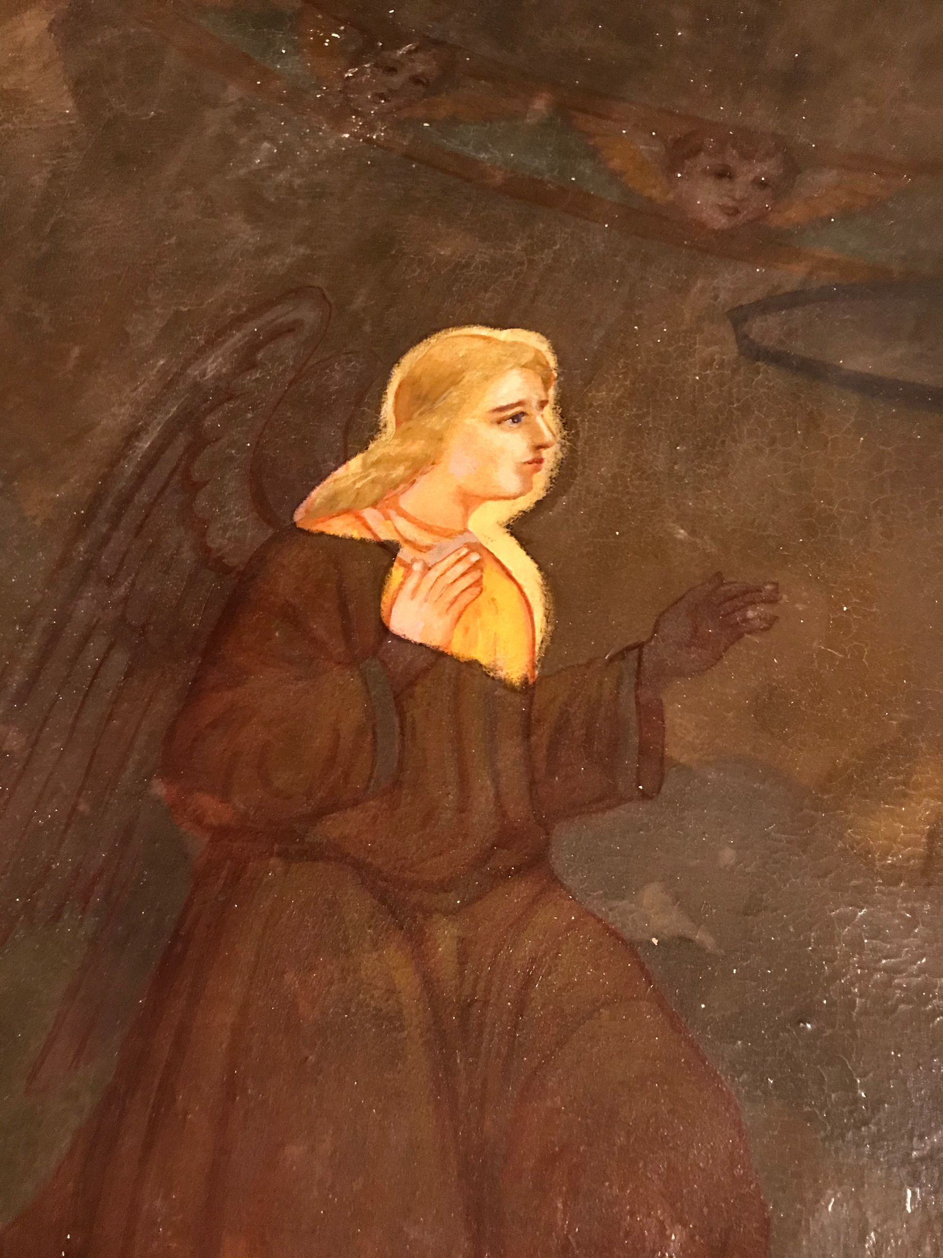 A close up of a painting of an angel with wings praying.