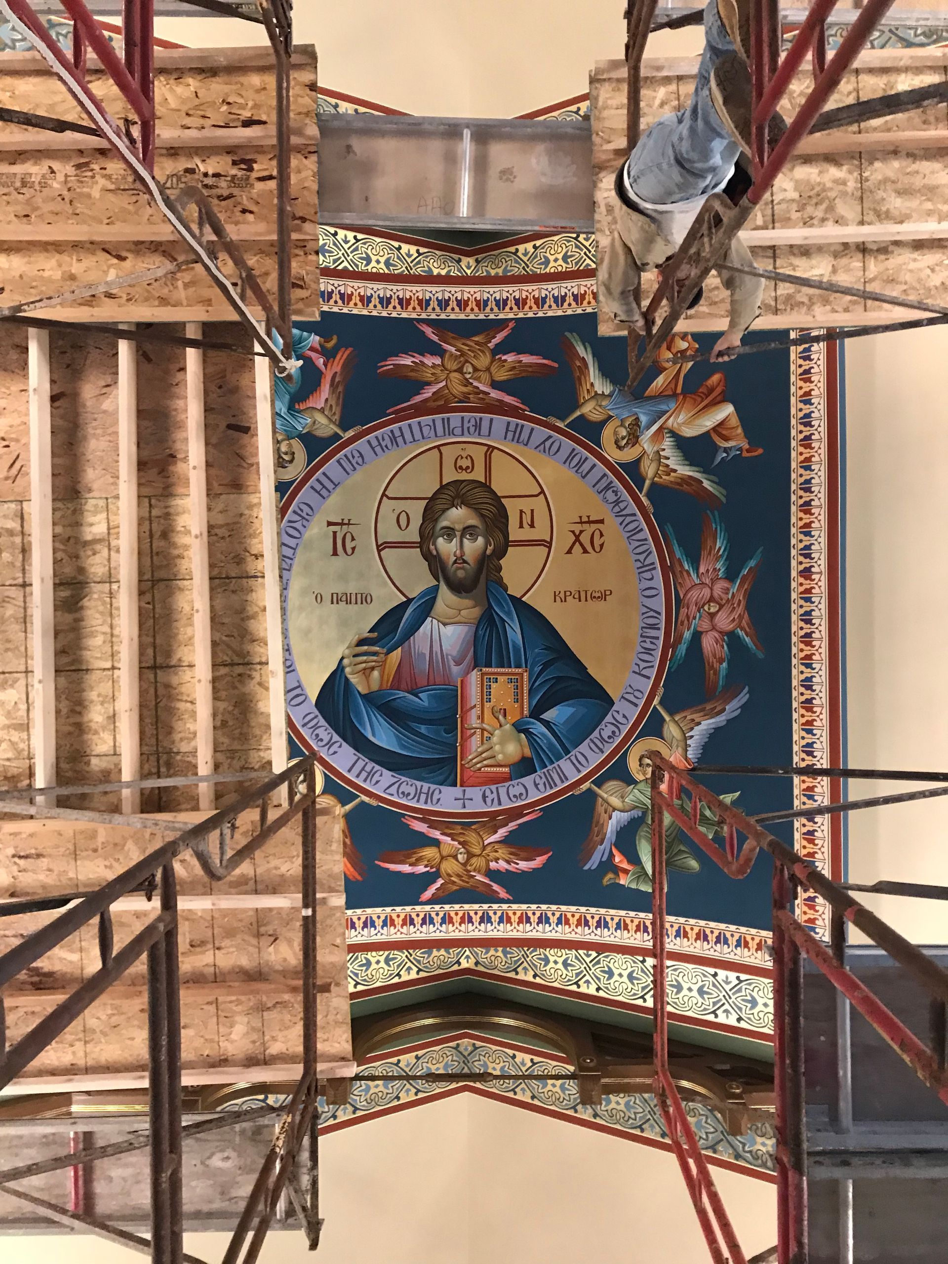 A painting of jesus is being painted on the ceiling of a church.