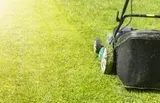 A lawn mower is cutting a lush green lawn.