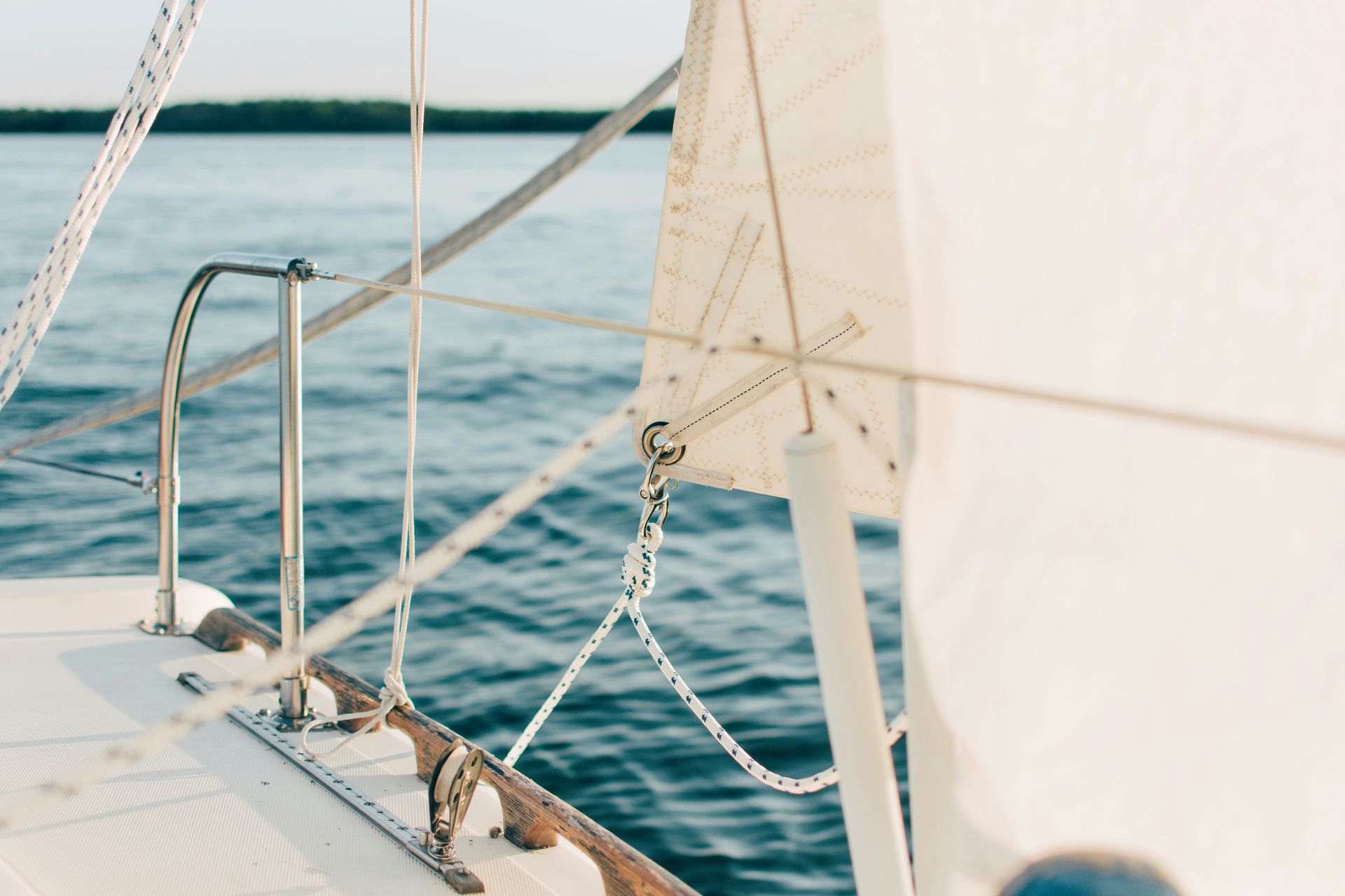 Sailboat sailing on blue water, white sail, sunny day.