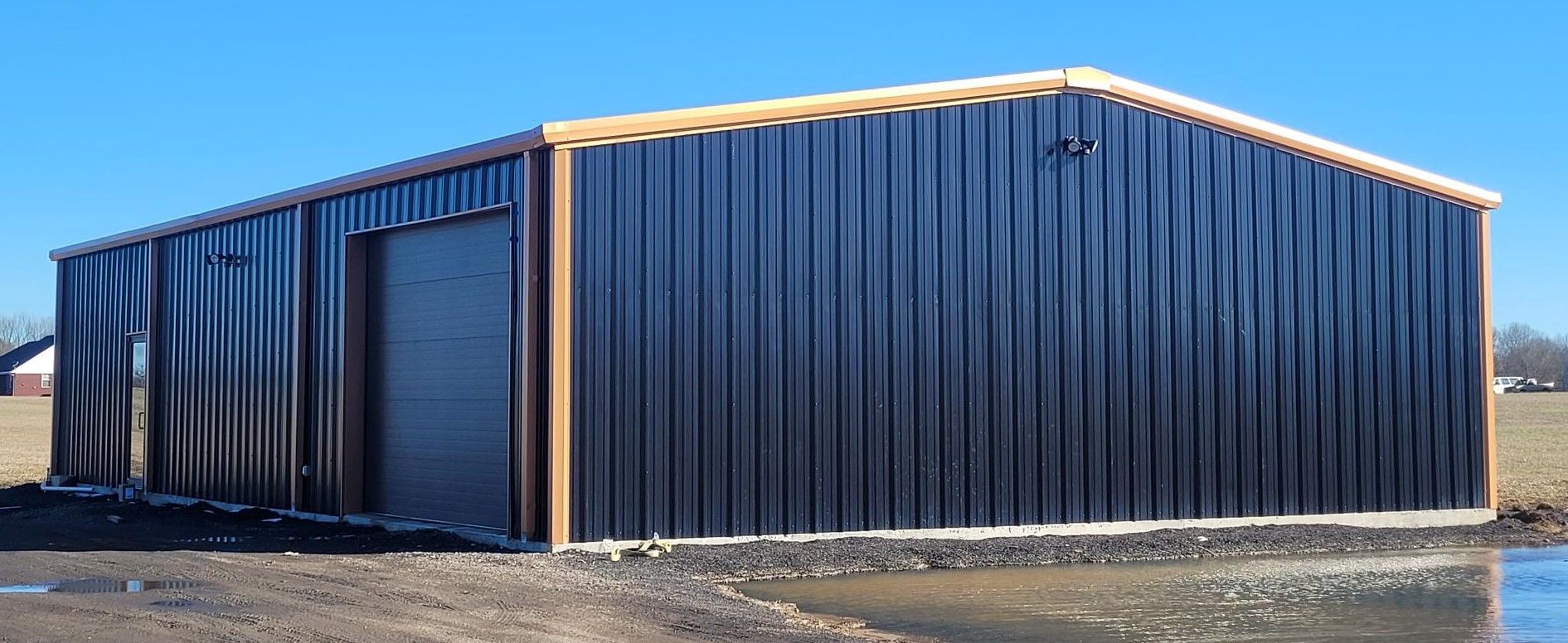 Custom barndominium building with black metal siding and copper trim