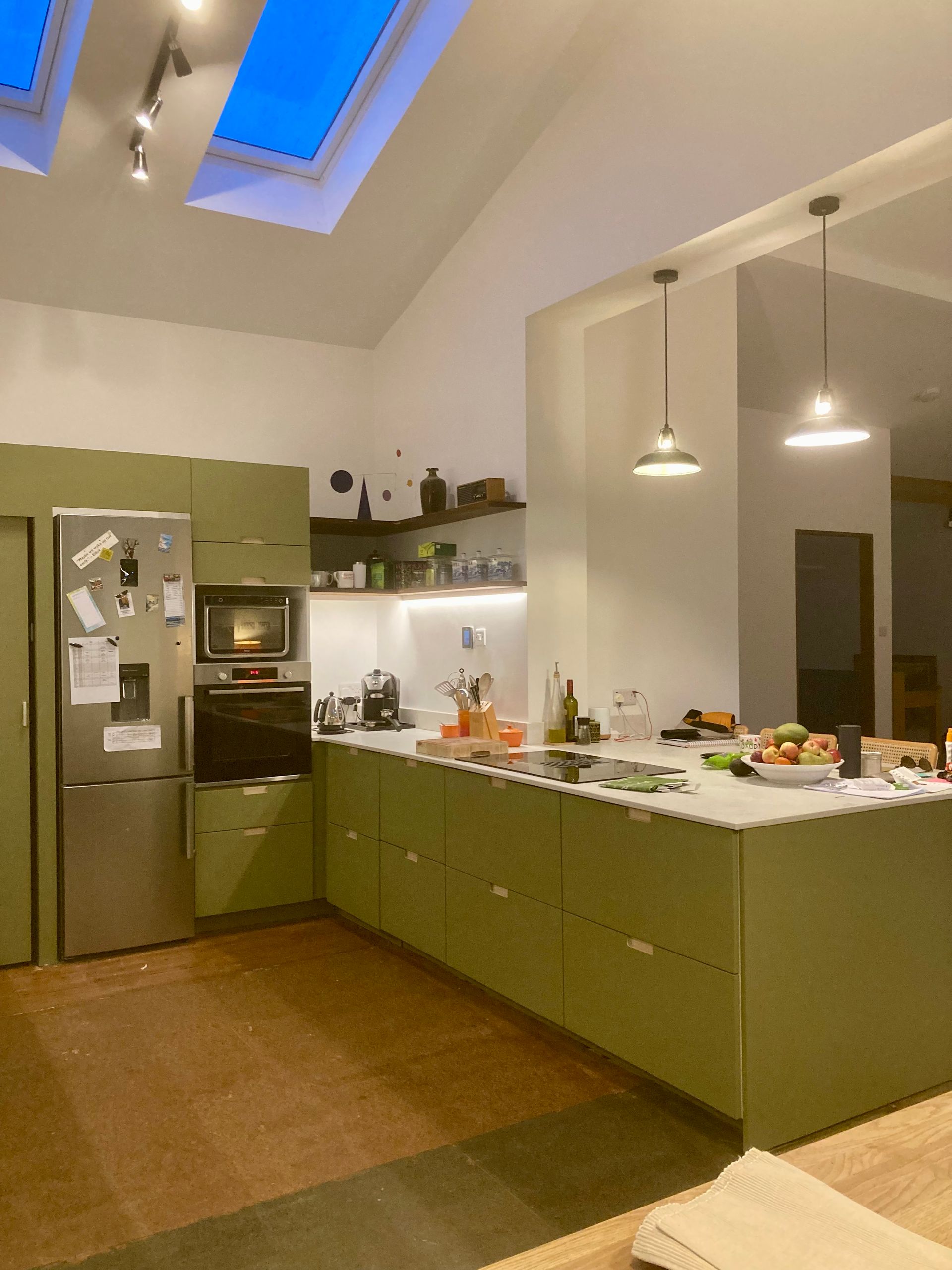 A kitchen with green cabinets and stainless steel appliances