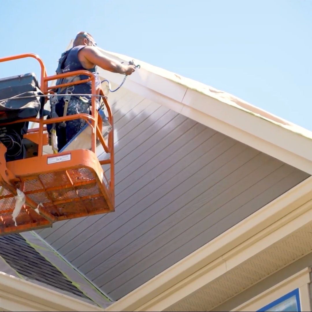Un homme peint le toit d'une maison
