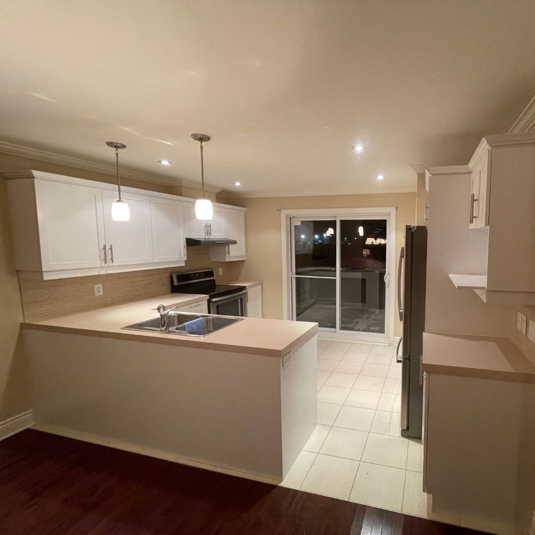 Une cuisine avec des armoires blanches et une porte coulissante en verre