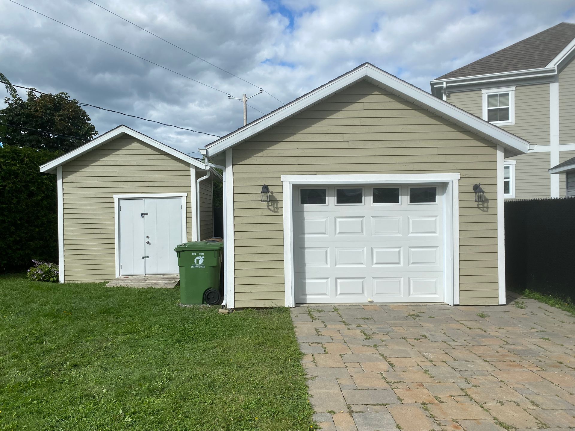 Un garage avec une poubelle verte devant