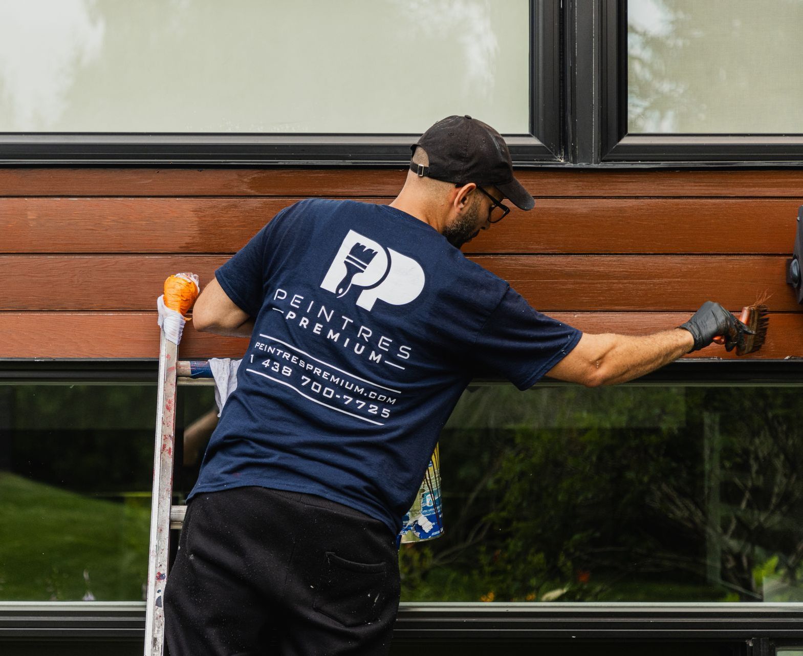 Un homme est debout sur une échelle et peint un bâtiment.