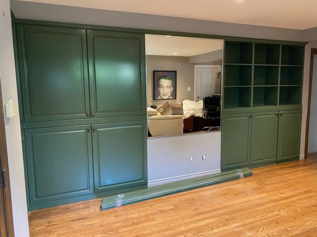 Un salon avec des armoires vertes et une porte coulissante en verre menant à un salon.