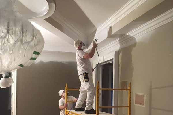 Un homme est debout sur un échafaudage et peint un mur.
