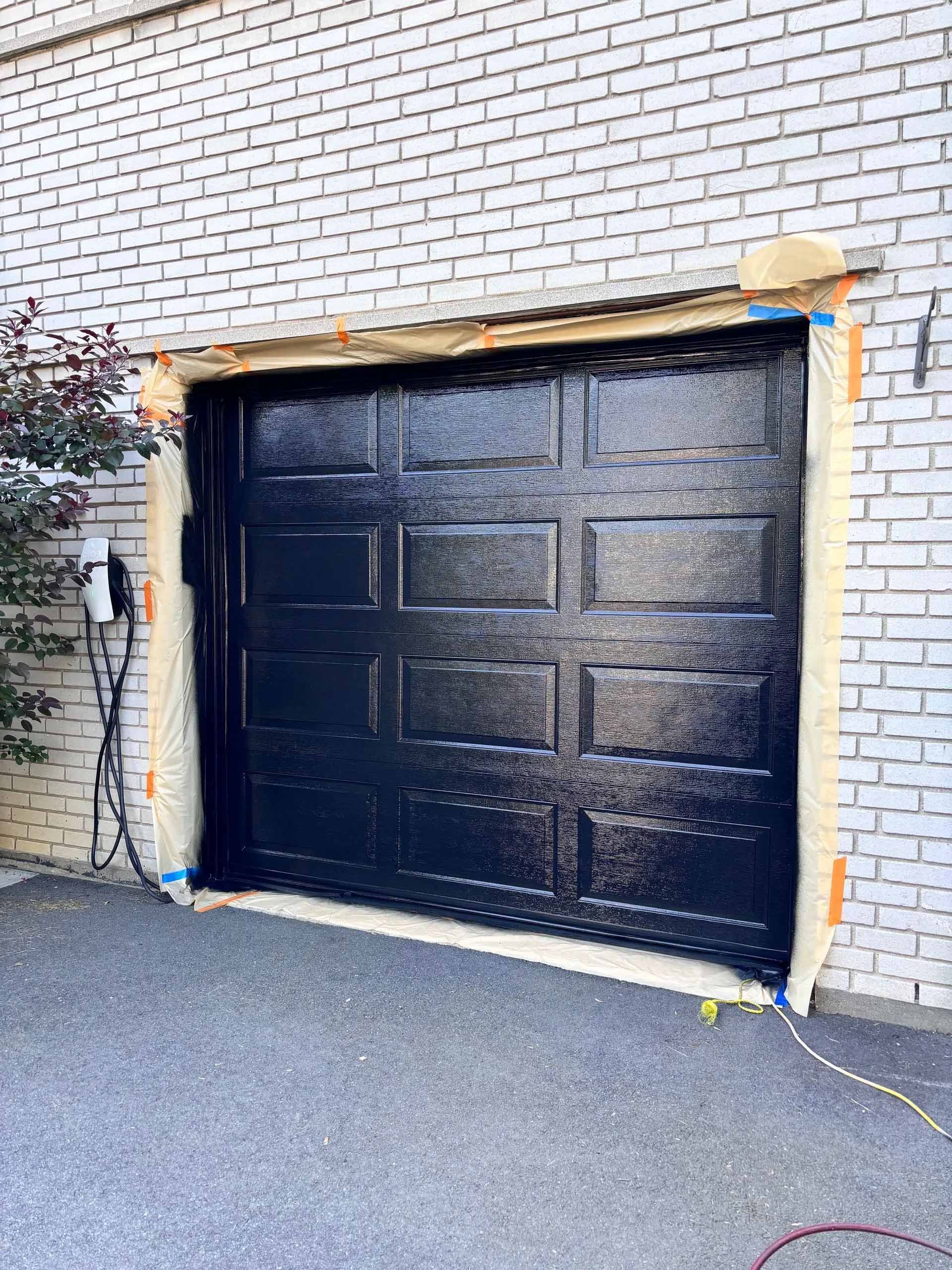 Une porte de garage noire se trouve sur un bâtiment en briques.