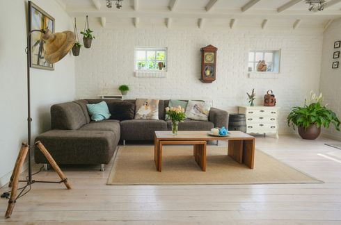 A living room with a couch , two coffee tables and a clock on the wall.