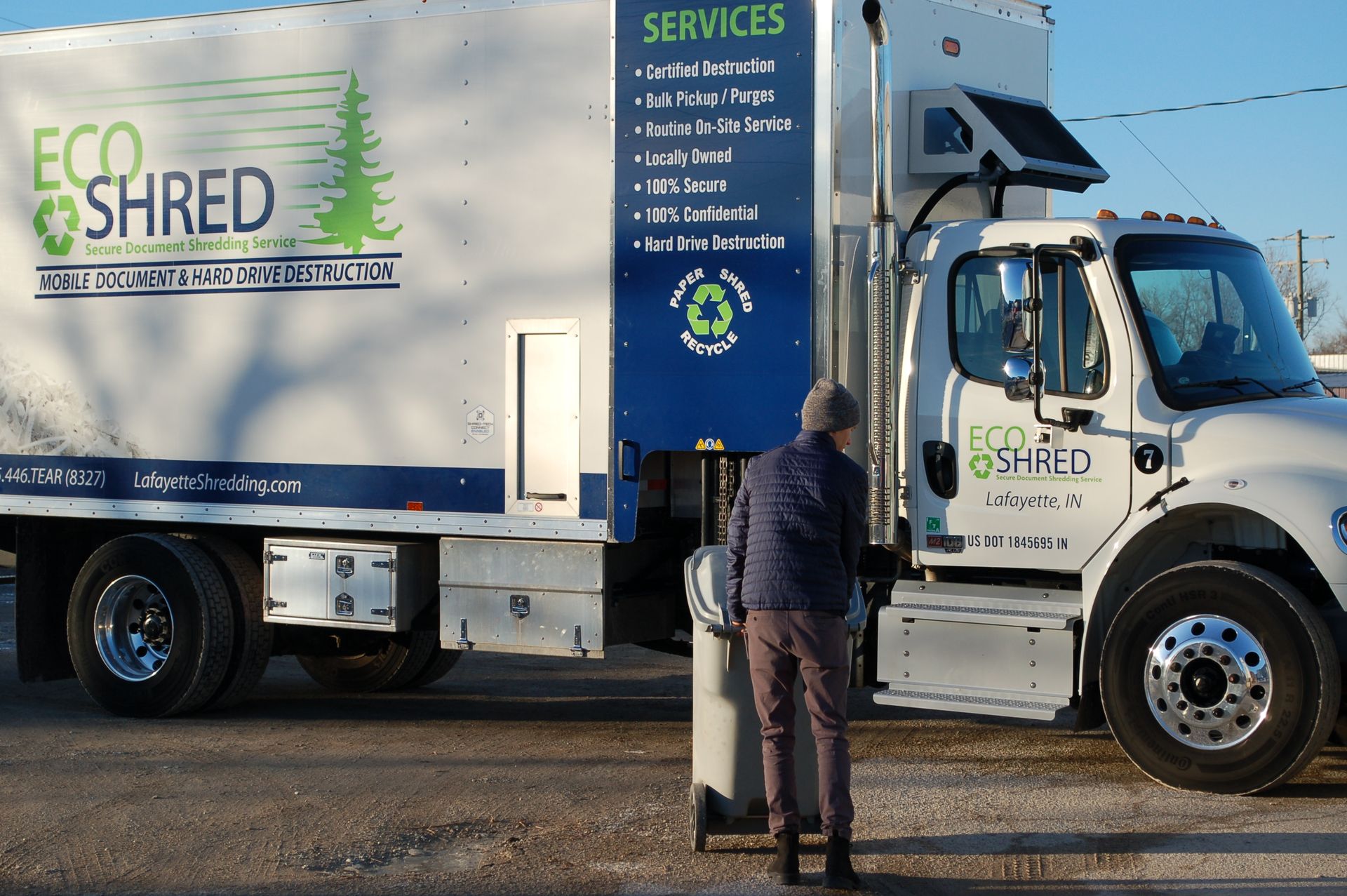A person is holding a transparent container of shredded paper.