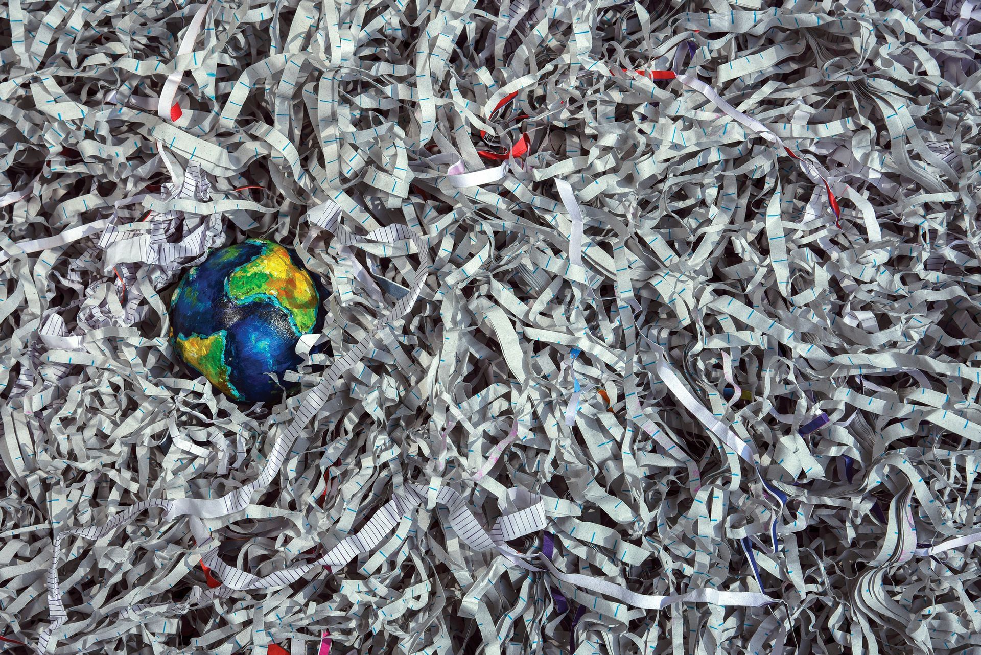 Toy earth surrounded by shredded paper.