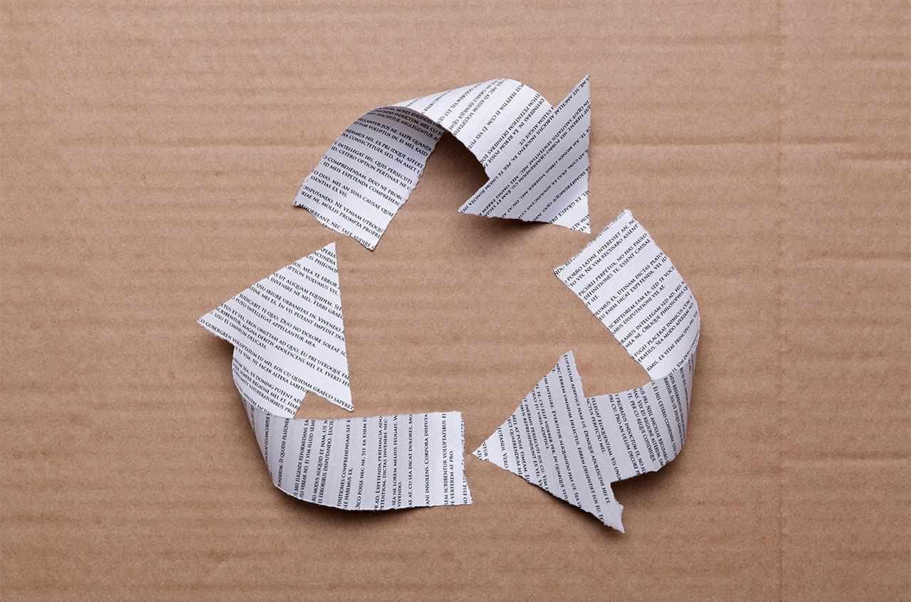 Recycling symbol made by cut out arrows of discarded documents. 