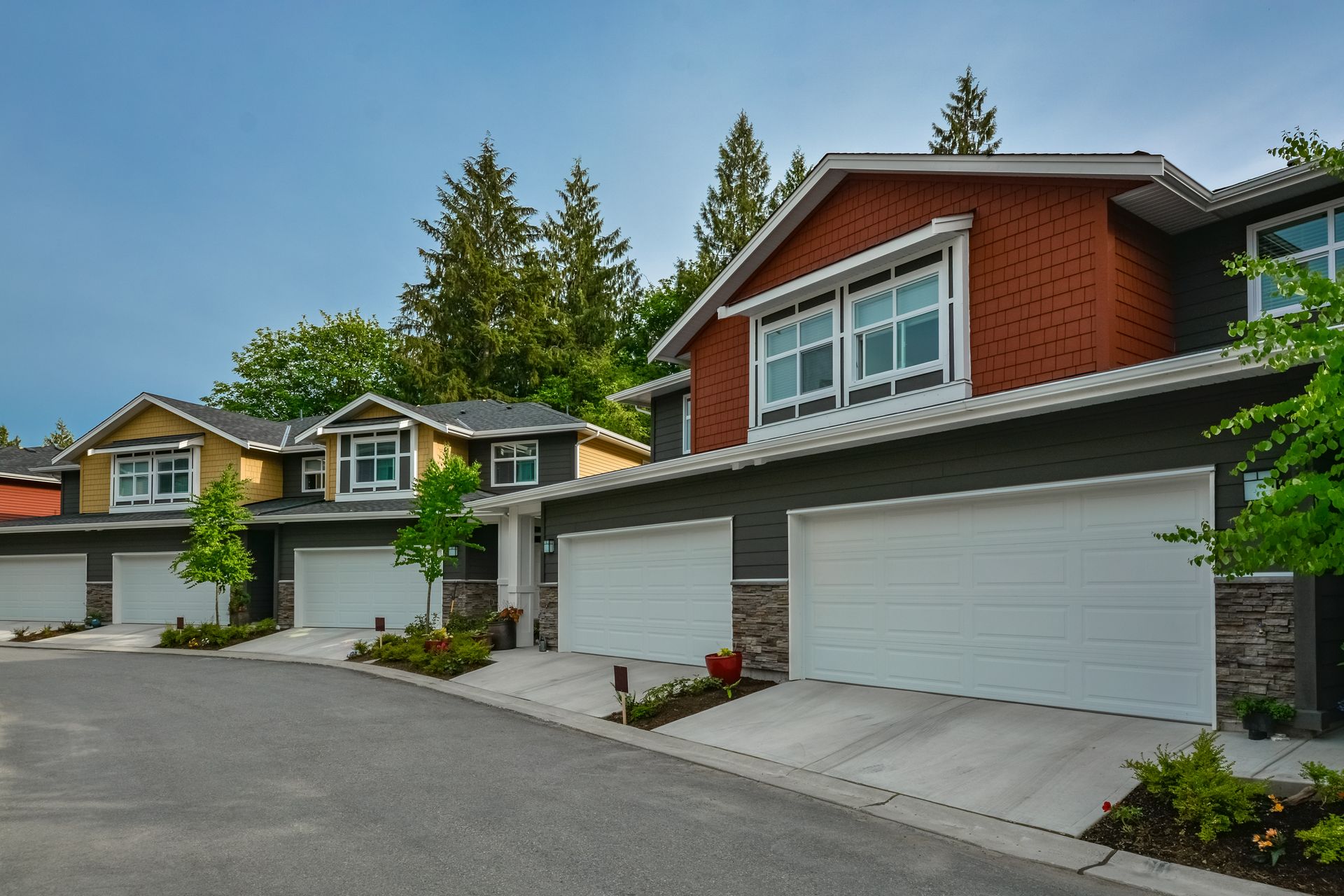 Two-car garage with dark gray doors and frosted glass windows, gray siding, and wooden accents.