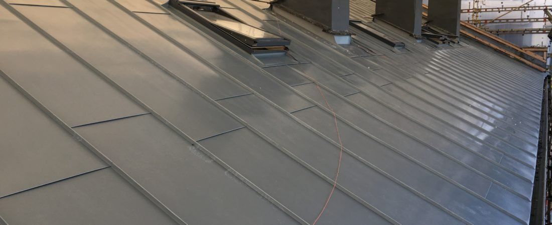 A close up of a metal roof with a skylight on it.