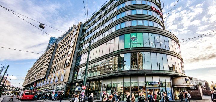 A large building with a lot of windows is on the corner of a city street.