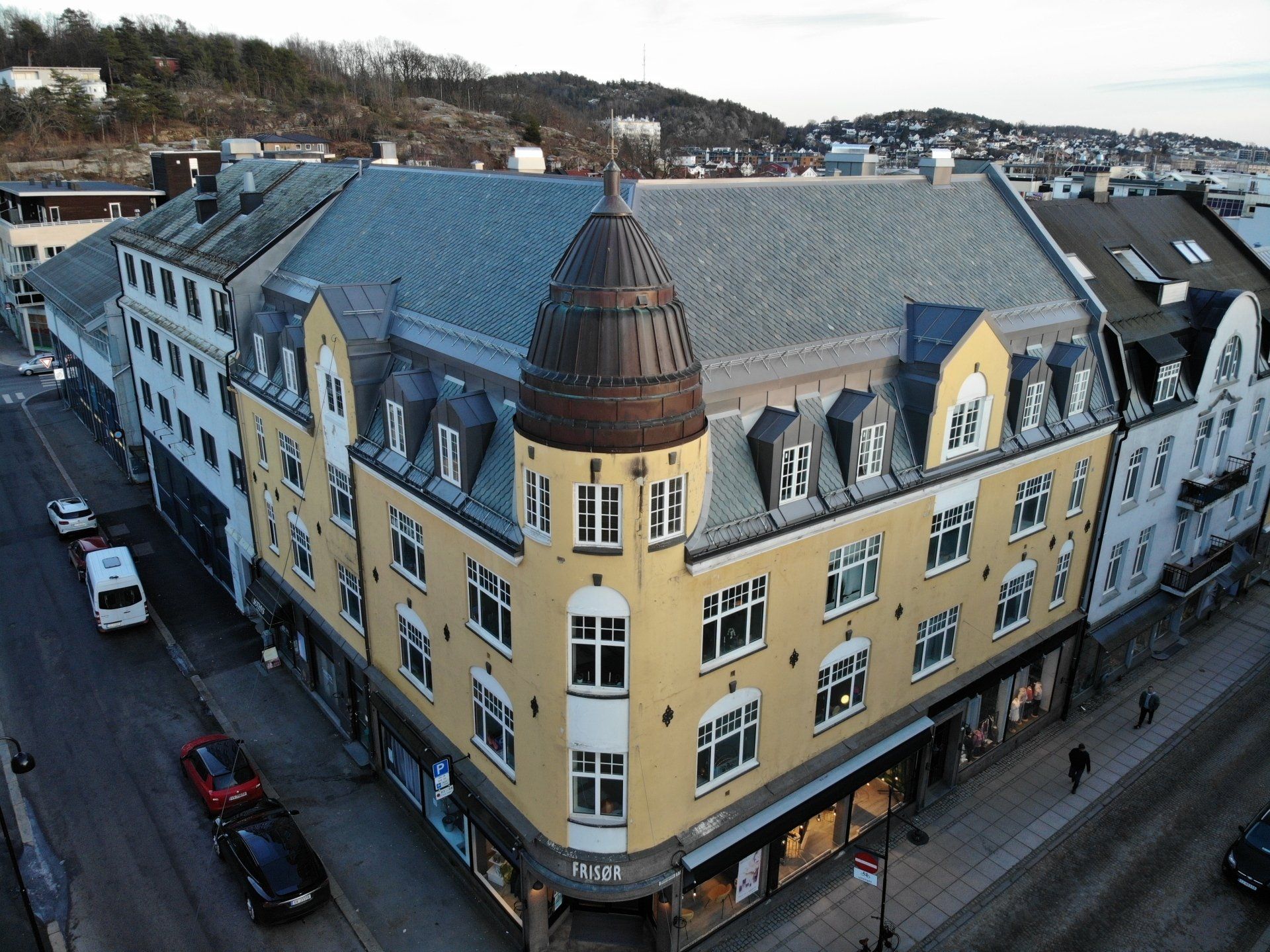 An aerial view of a large yellow building with a copper roof