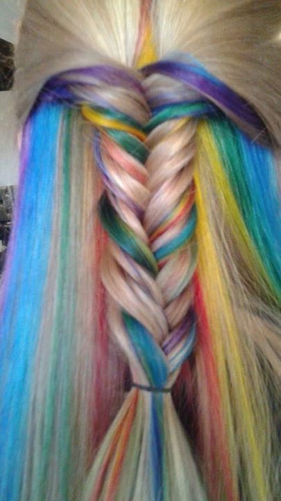 A close up of a woman 's braided hair with rainbow colored hair extensions.