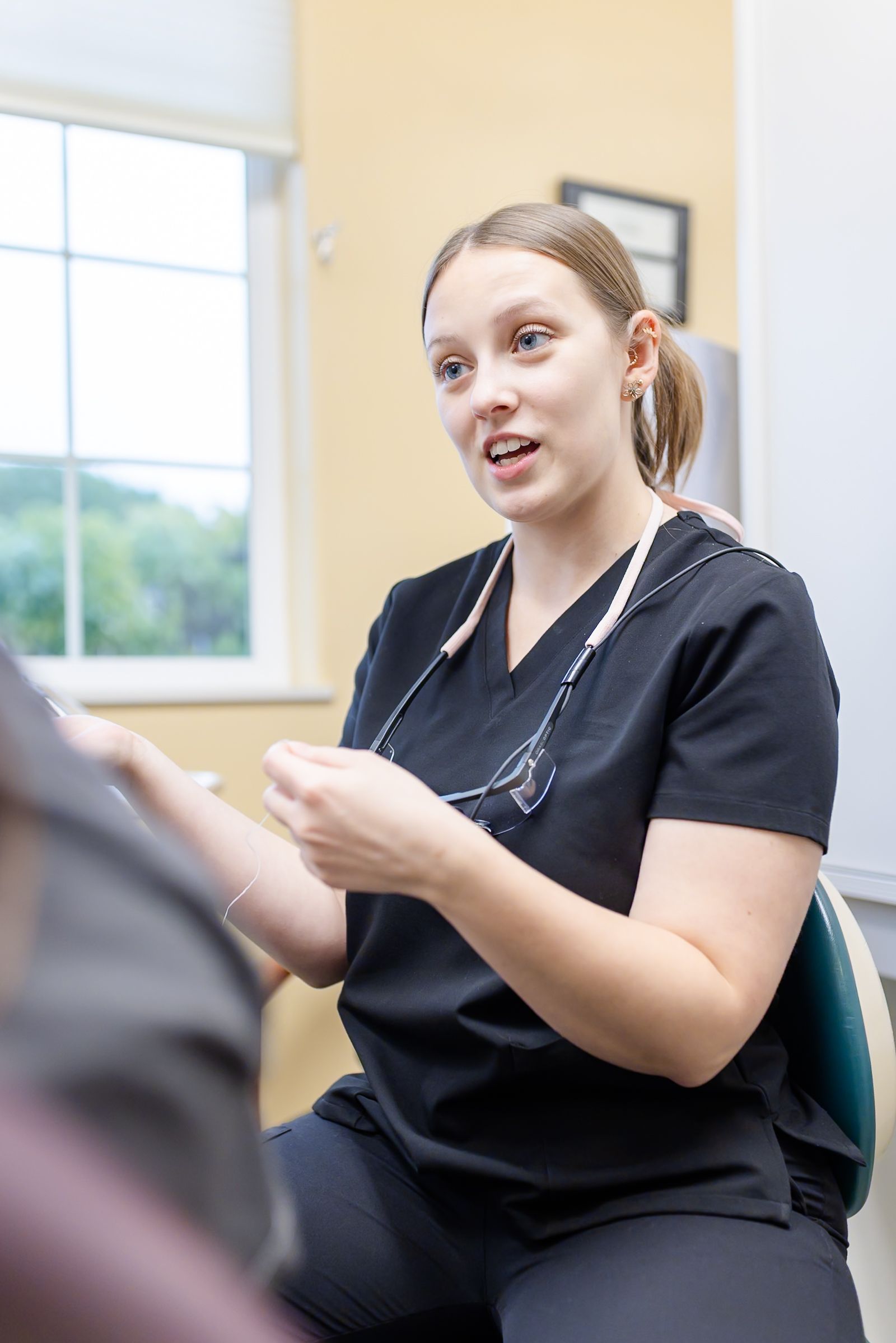 Dentist and assistant examining a patient's teeth in an office setting. They are wearing masks and gloves.