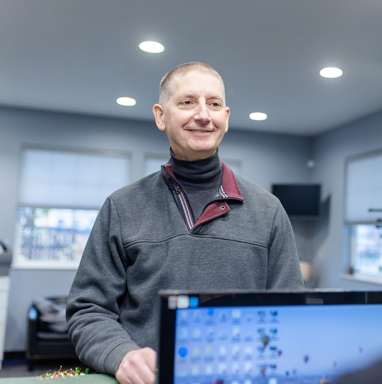 Woman smiling, looking at her reflection in a large, ornate mirror. Orange shirt, light-filled room.
