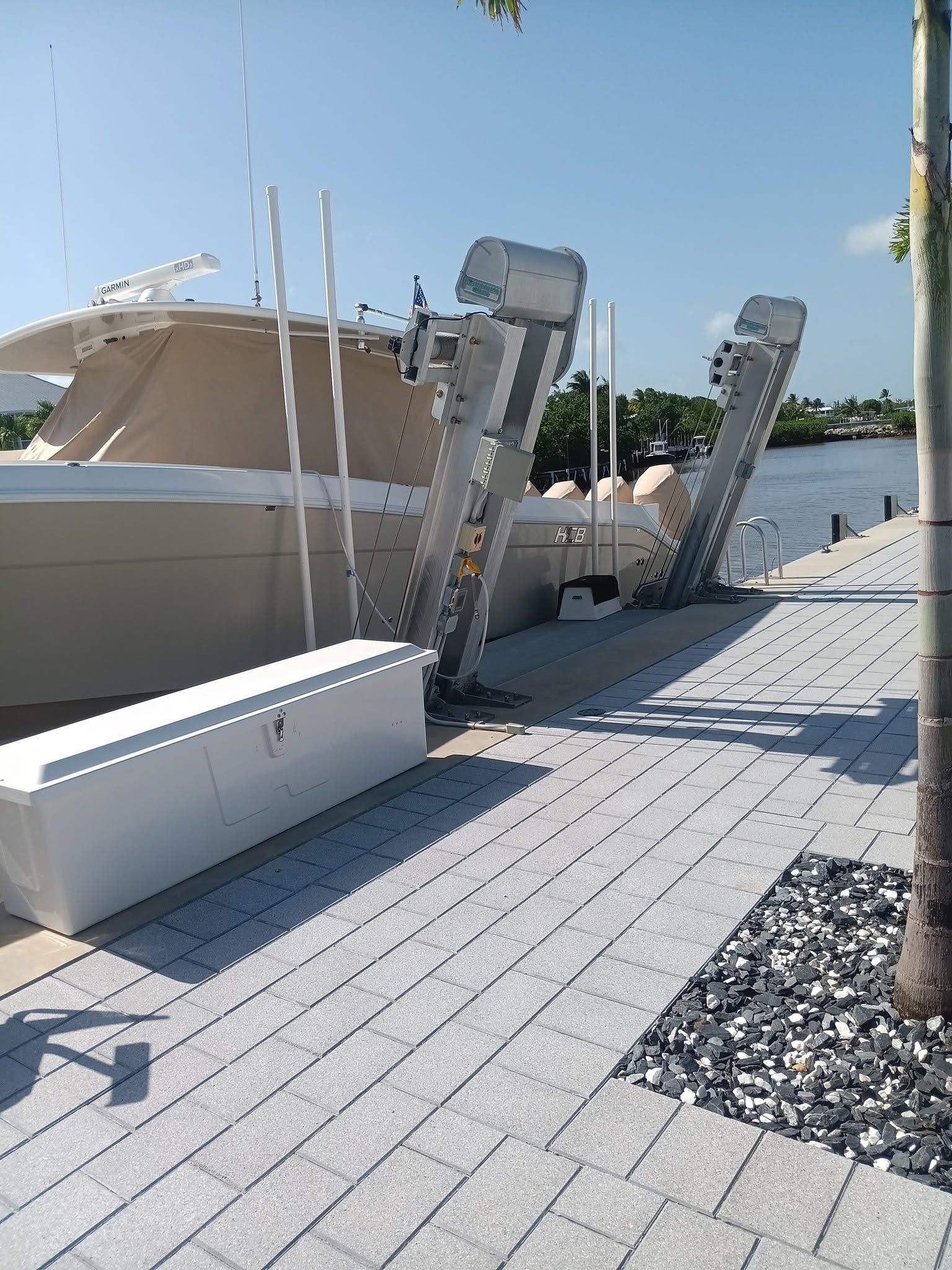 Broken dock pilings beside a white boat at a sunny marina, with debris on the walkway