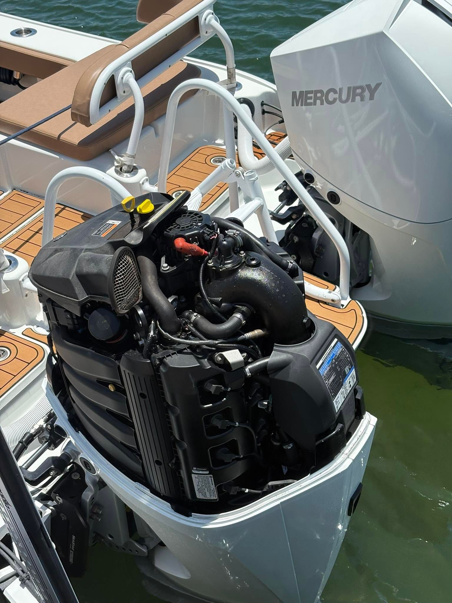 Mercury outboard motor mounted on a boat at a dock, with engine cover lifted open.