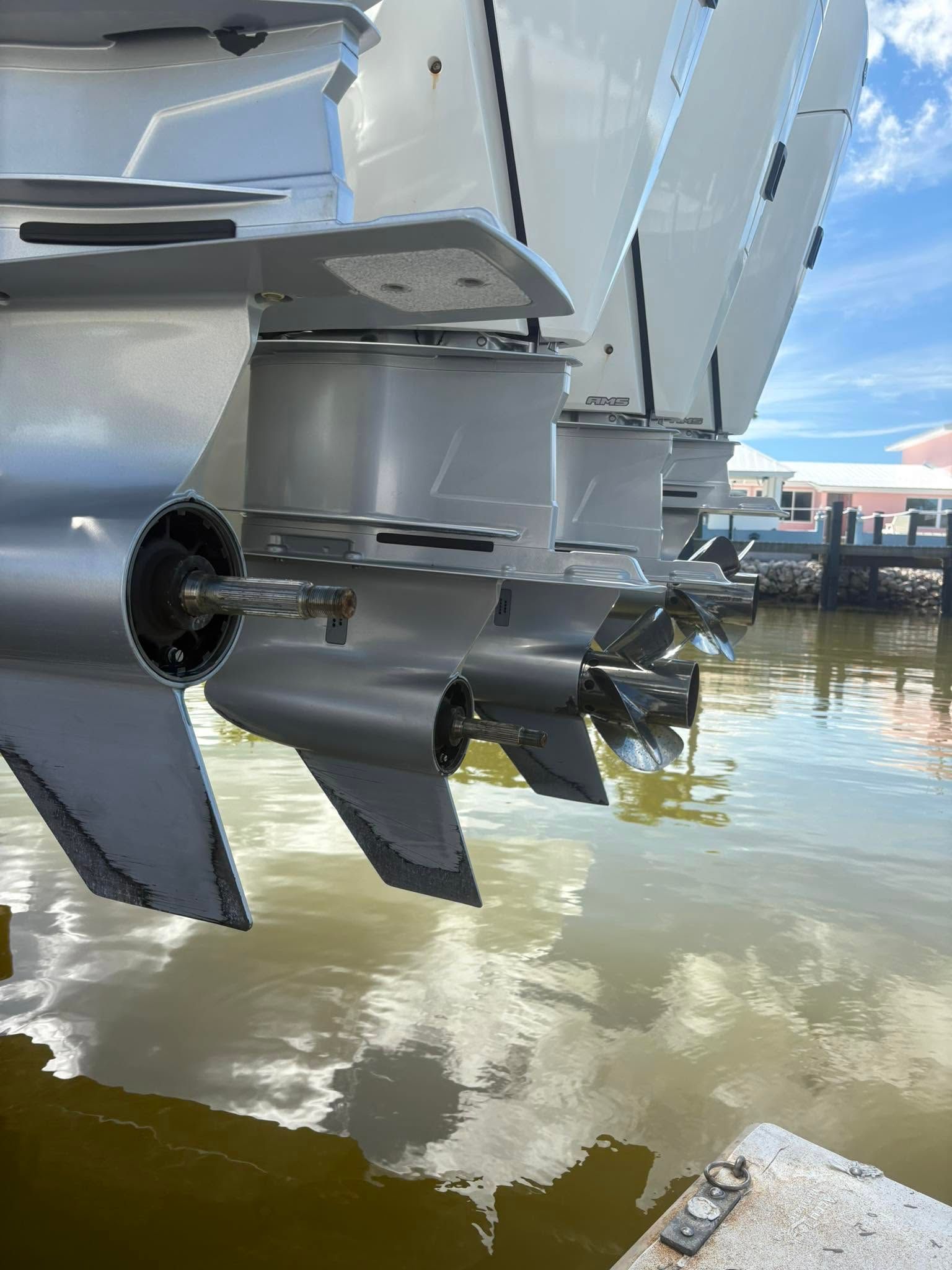 Close-up of a boat’s outboard motor and propeller over calm harbor water near a dock