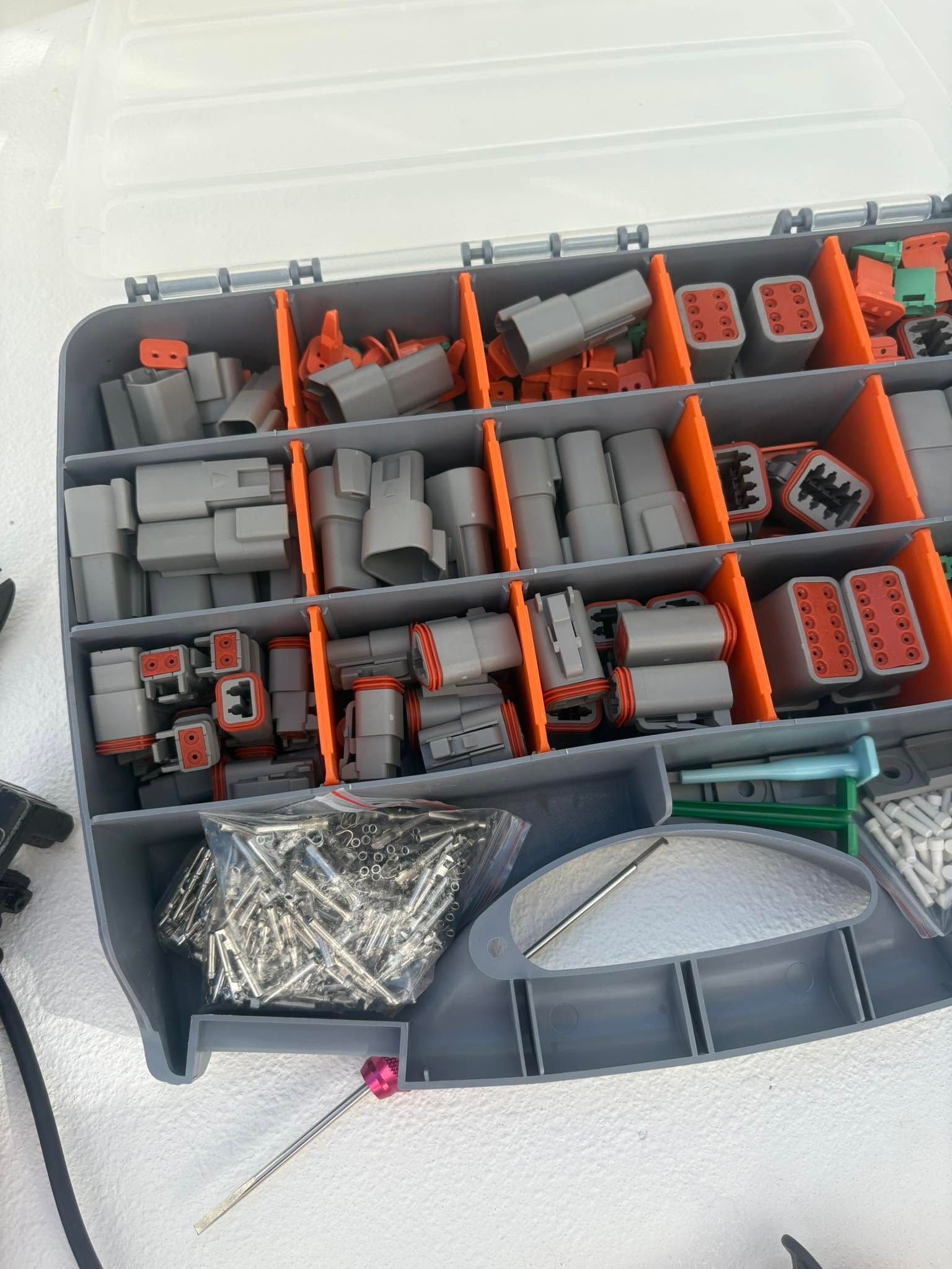 Open toolbox with orange dividers holding gray and orange parts, screws, and mesh pieces