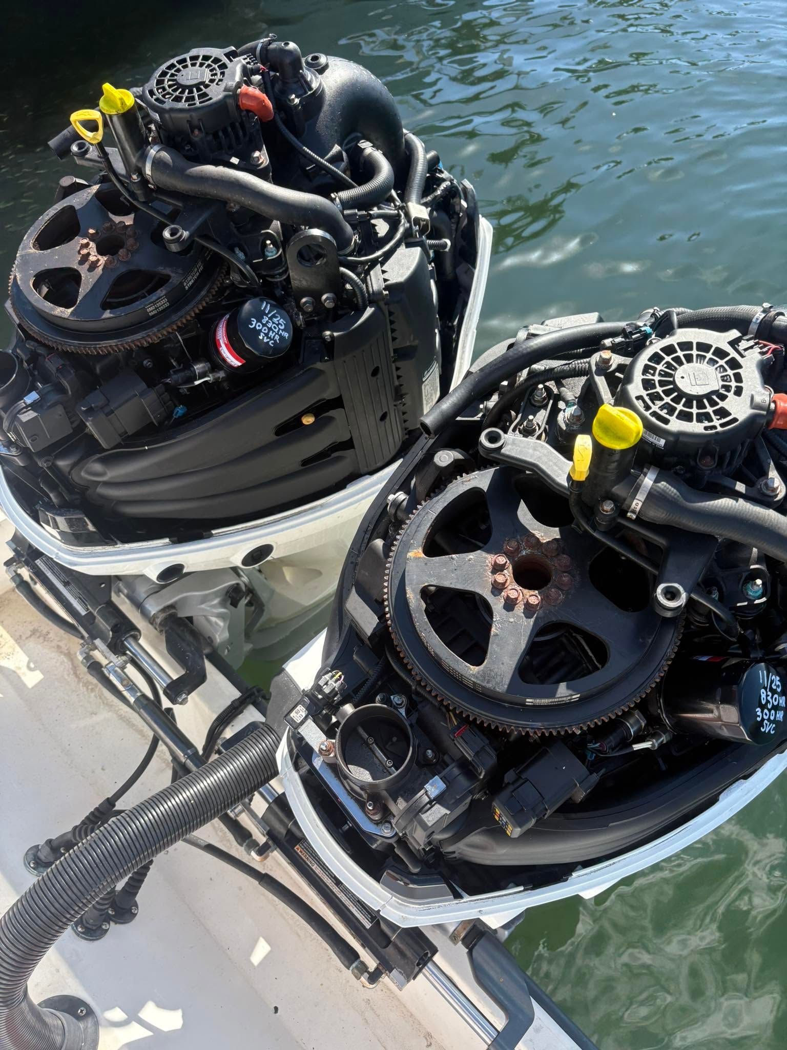Two outboard boat engines mounted on a dock above green water