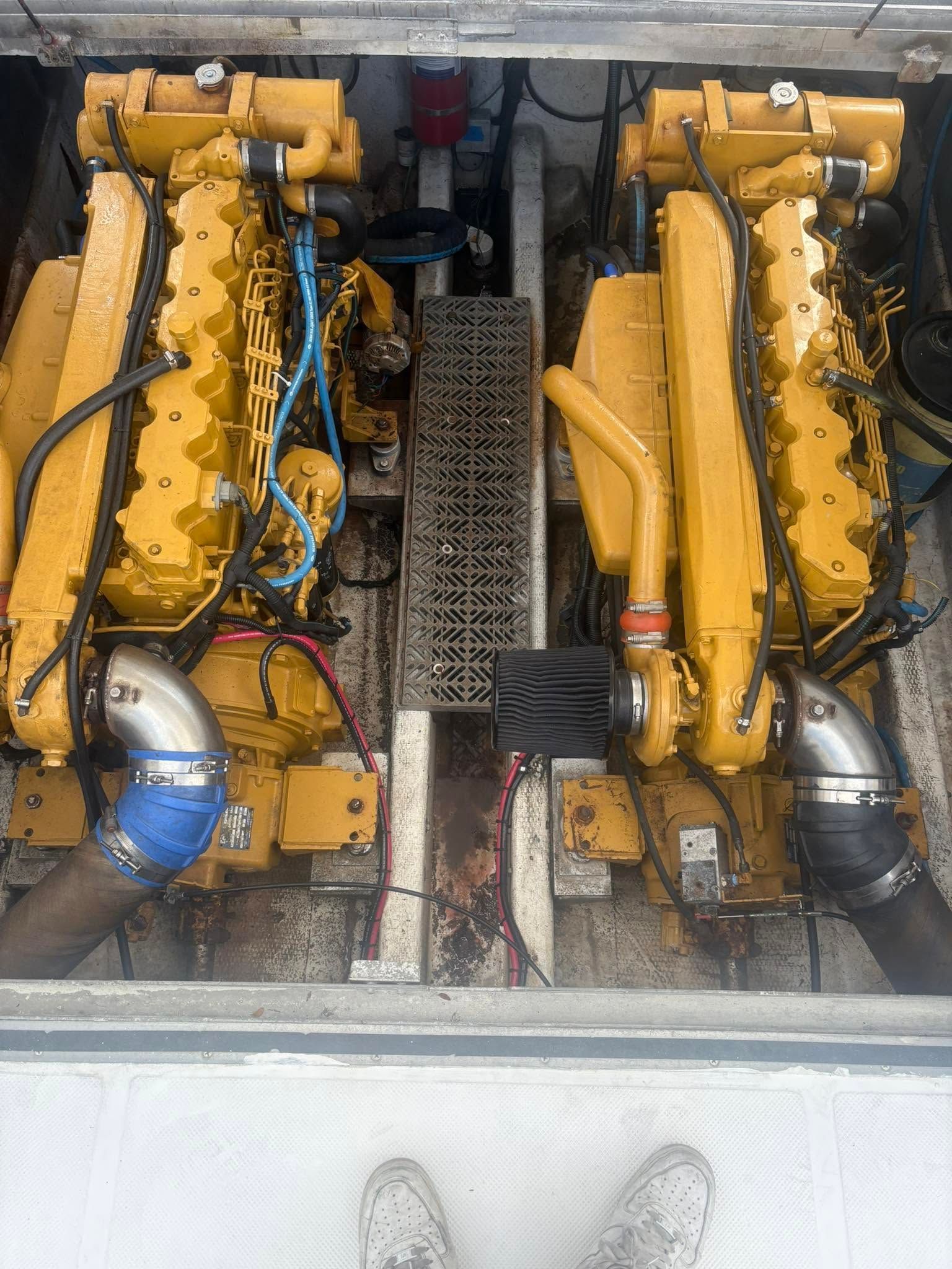 Two yellow engines side by side in a machinery compartment with blue and silver pipes.