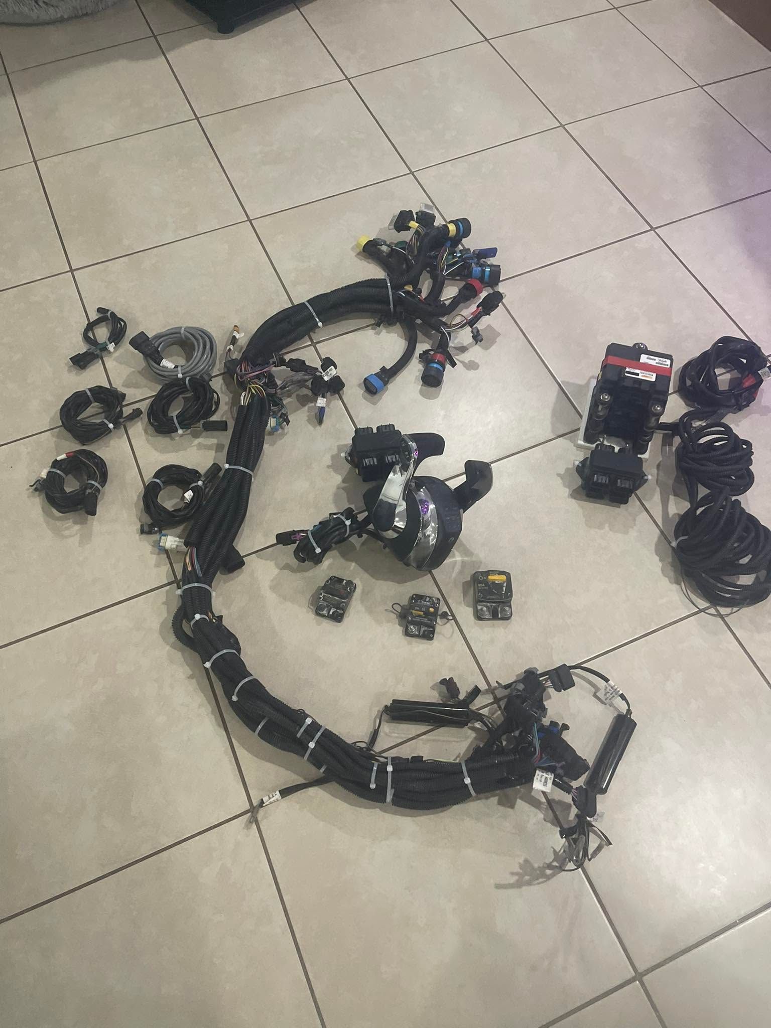 Black electronic parts and cables arranged on a tiled floor in a loose circle.