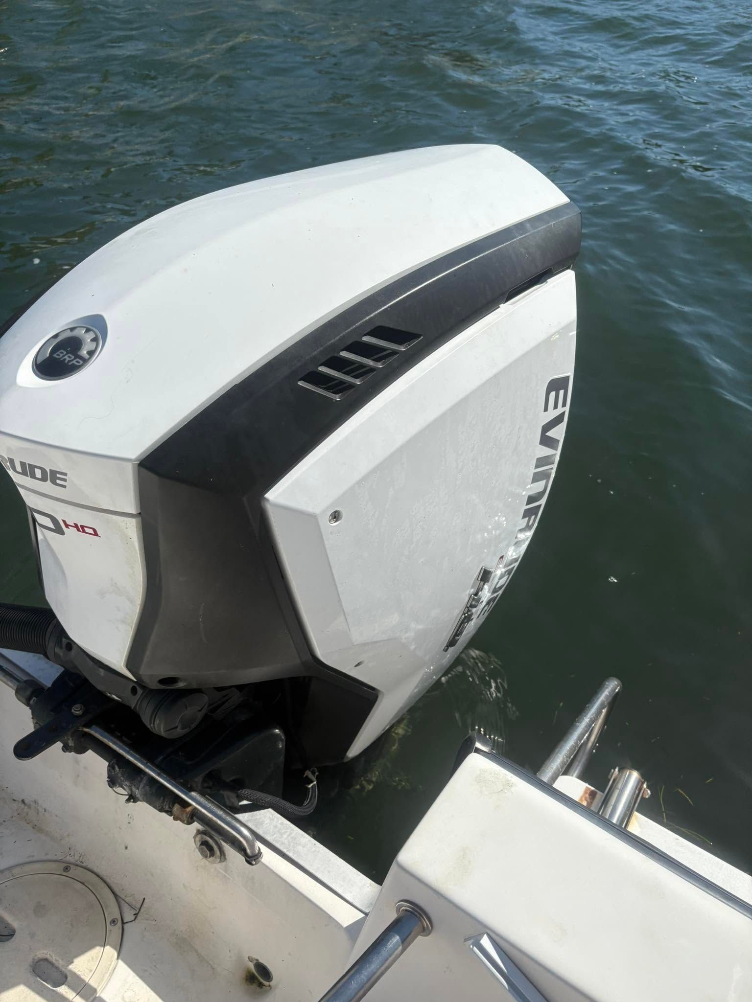 Close-up of a white outboard motor mounted on a boat, floating on dark blue water.