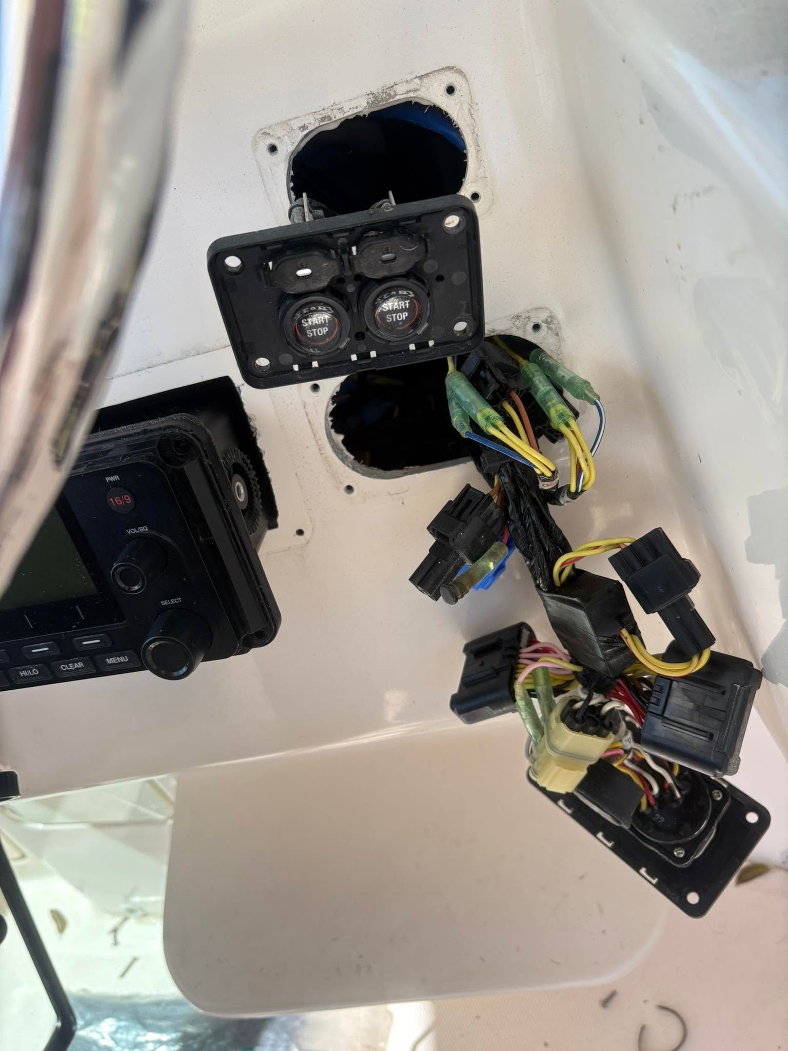 Detached wiring and black control panels inside a white vehicle ceiling panel.