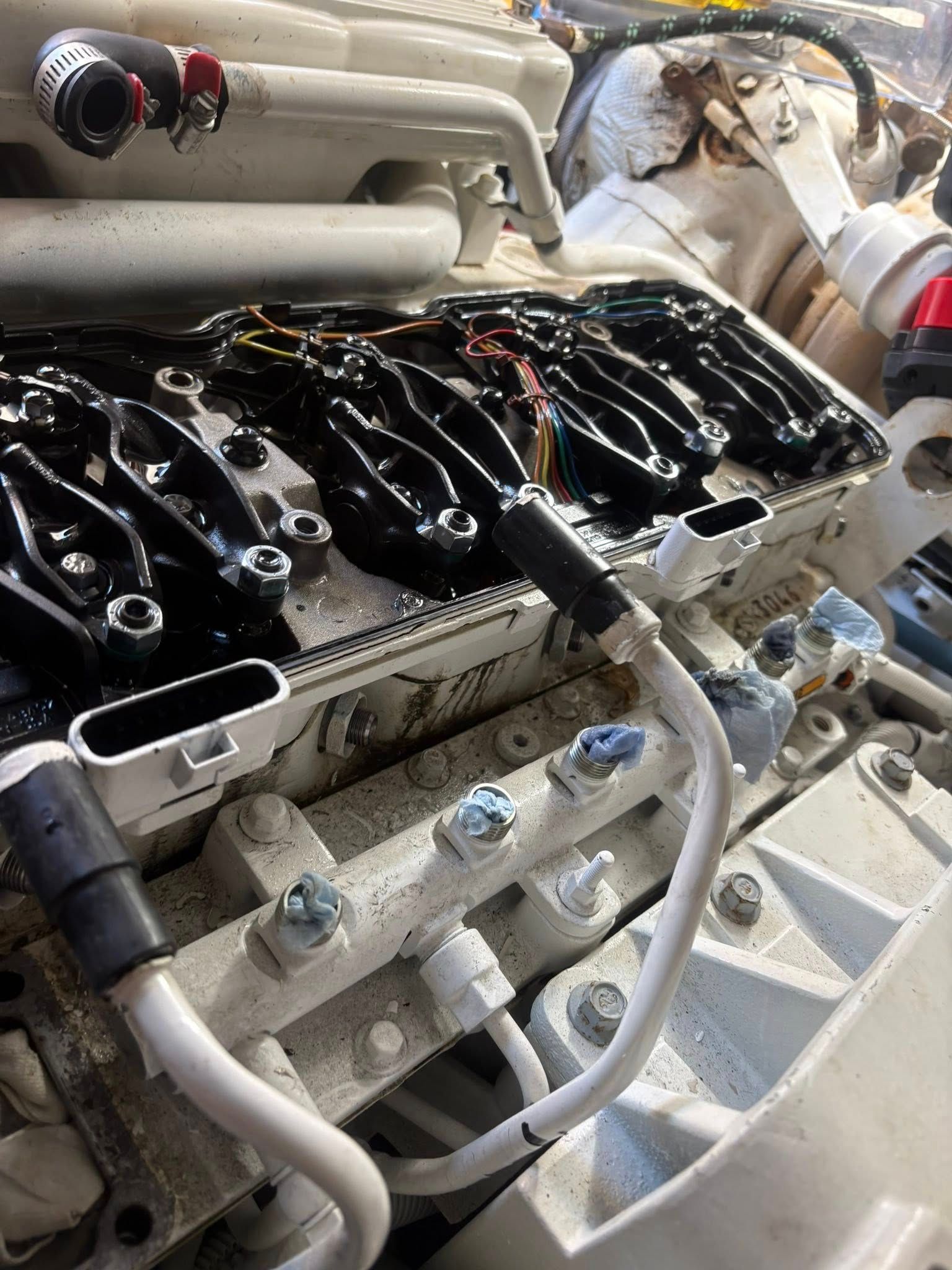Close-up of a white engine block with black glossy mechanical parts and hoses in a workshop