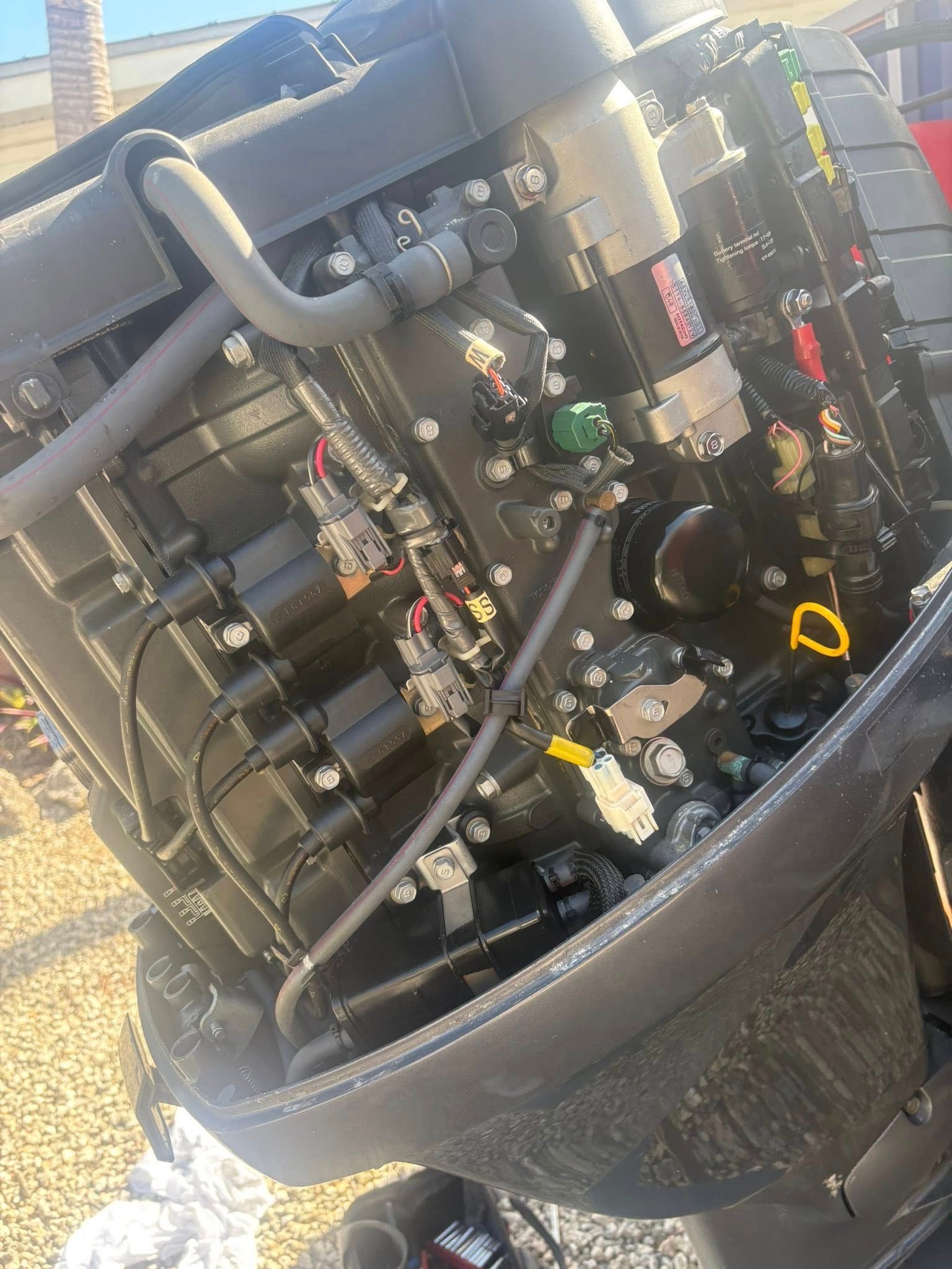 Close-up of a black mechanical engine or pump assembly with hoses, wires, and metal components in a case