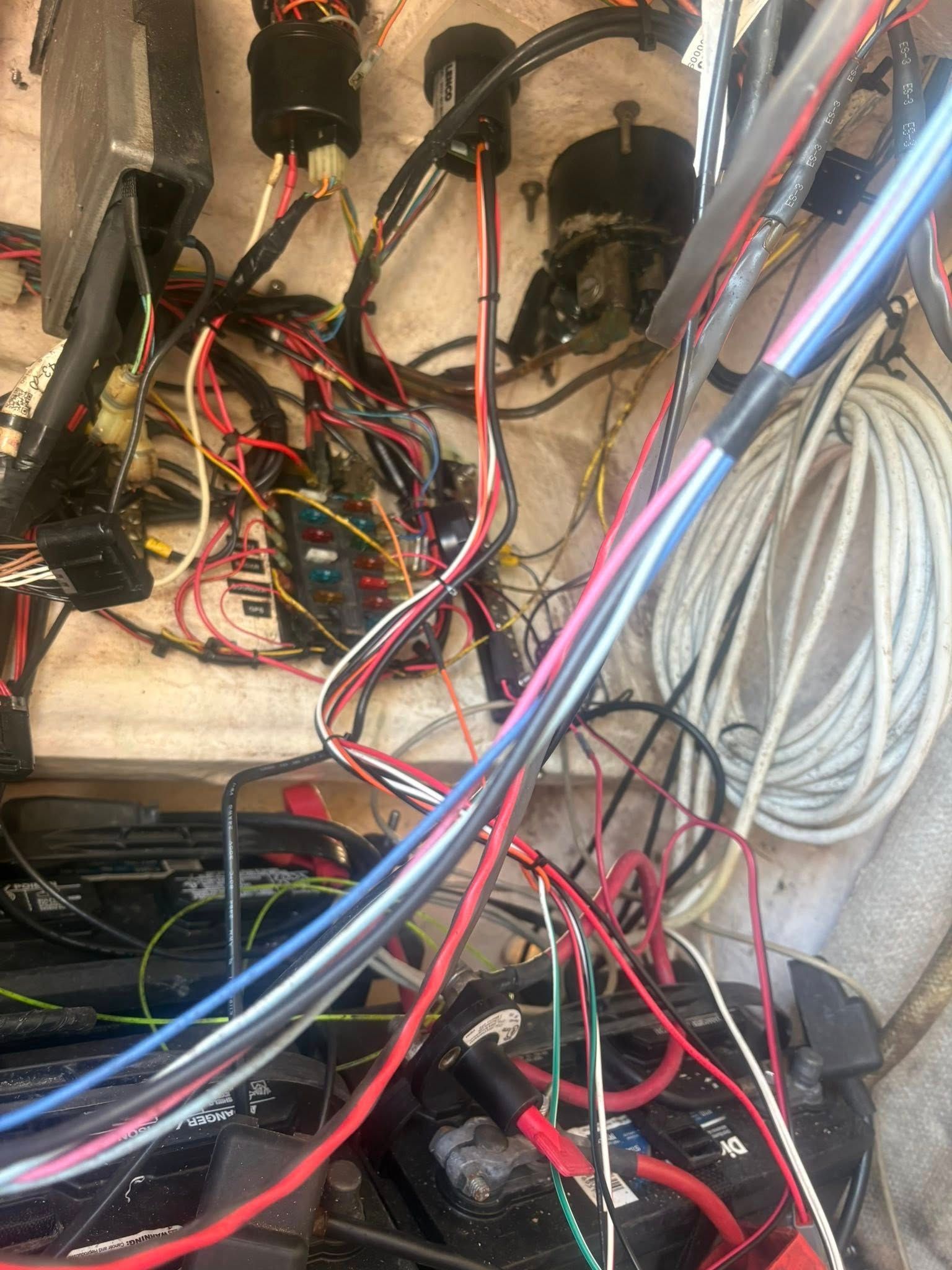 A dense tangle of multicolored electrical wires and cables inside a cramped equipment compartment.