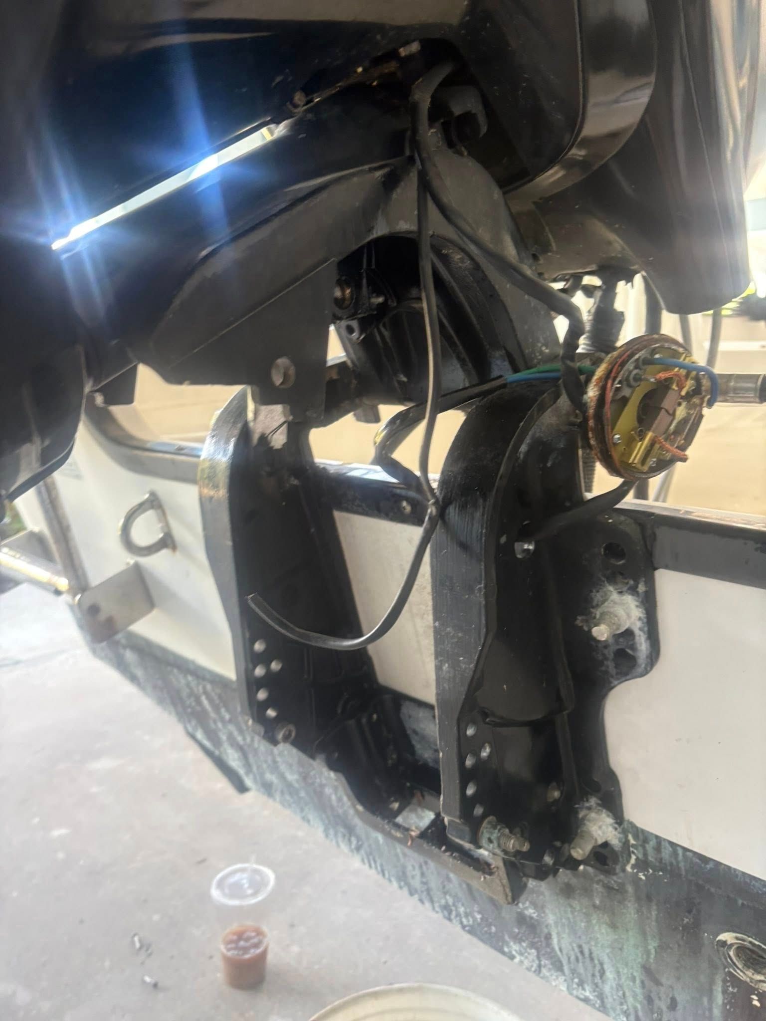 Close-up of a boat engine compartment with exposed black components and wiring near the hull.