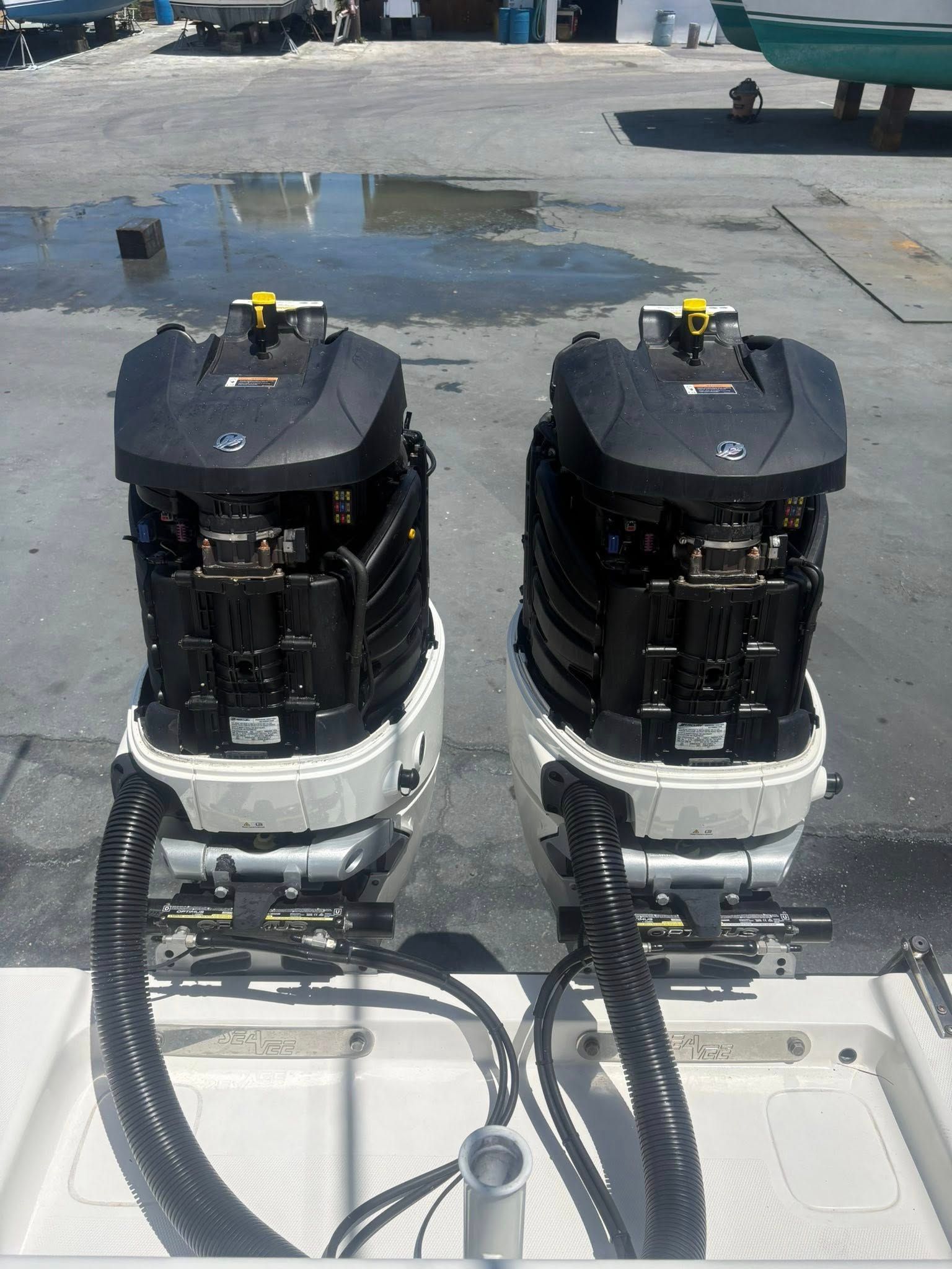 Two black-and-white marine engines mounted on a boat stern with hoses connected