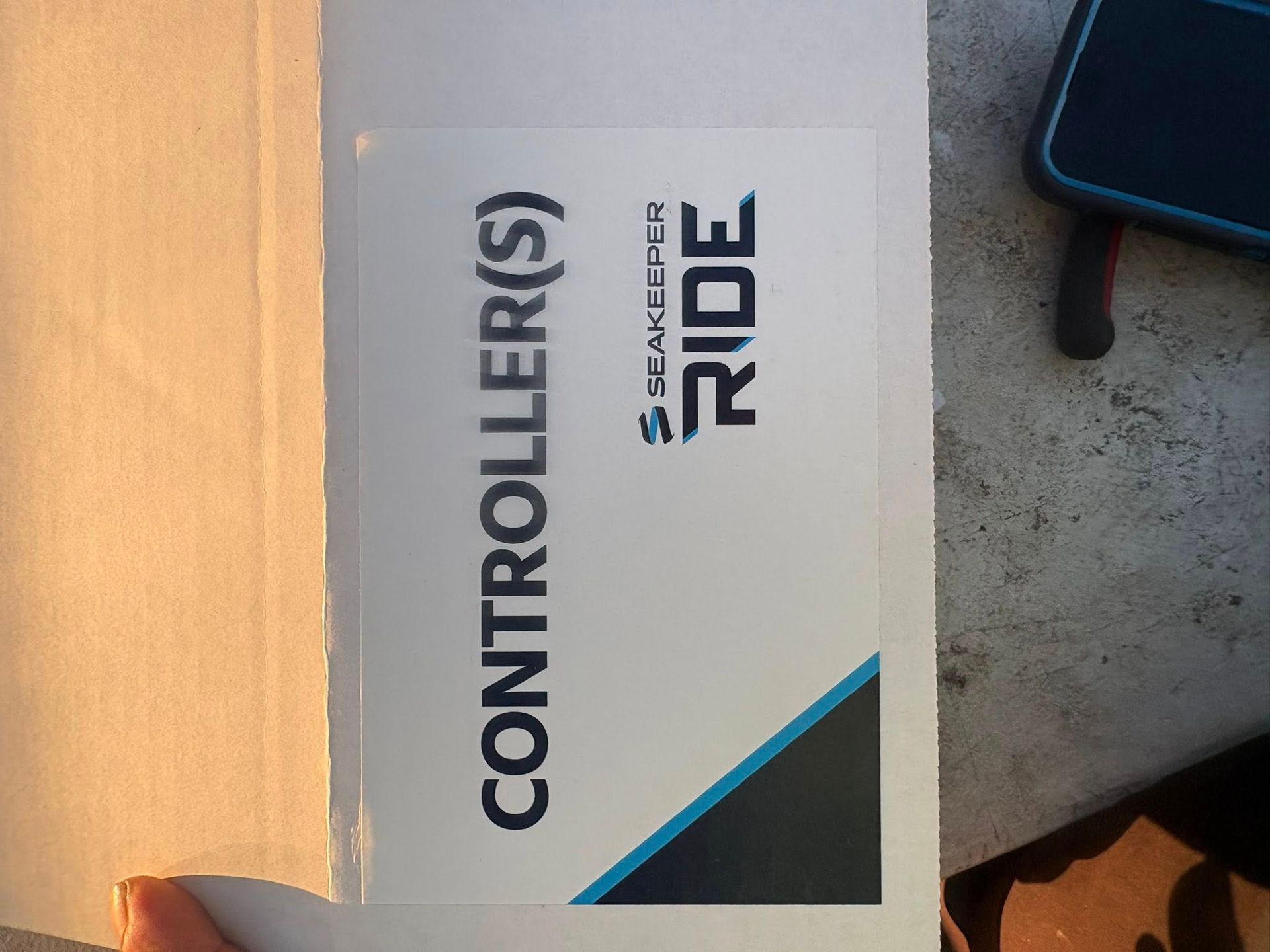 White box labeled “CONTROLLER(S) RIDE” on a floor, with a black object at the right edge.