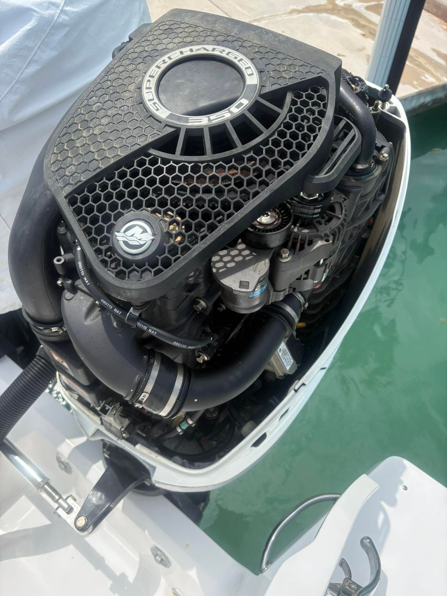 Close-up of a boat’s outboard engine with black protective cover above green water.