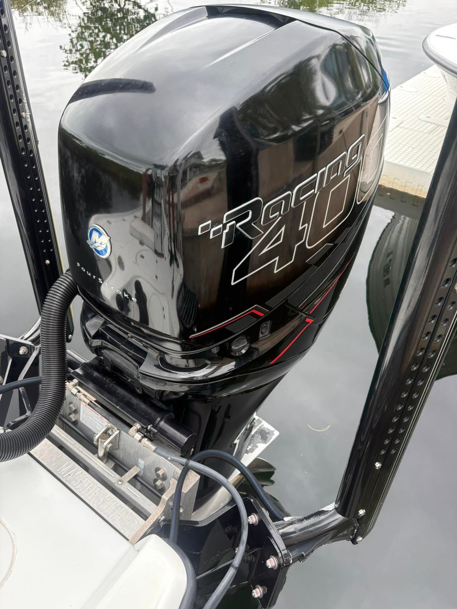 Black outboard motor mounted on a boat transom, with a white logo and metal support frame nearby