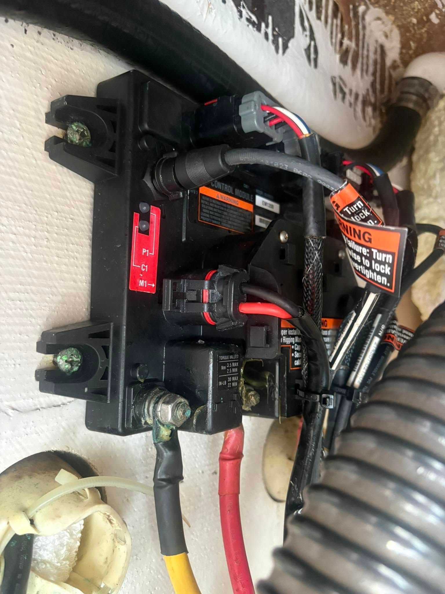 Compact electronics assembly with black and red wiring mounted on a wall, with a green valve below.