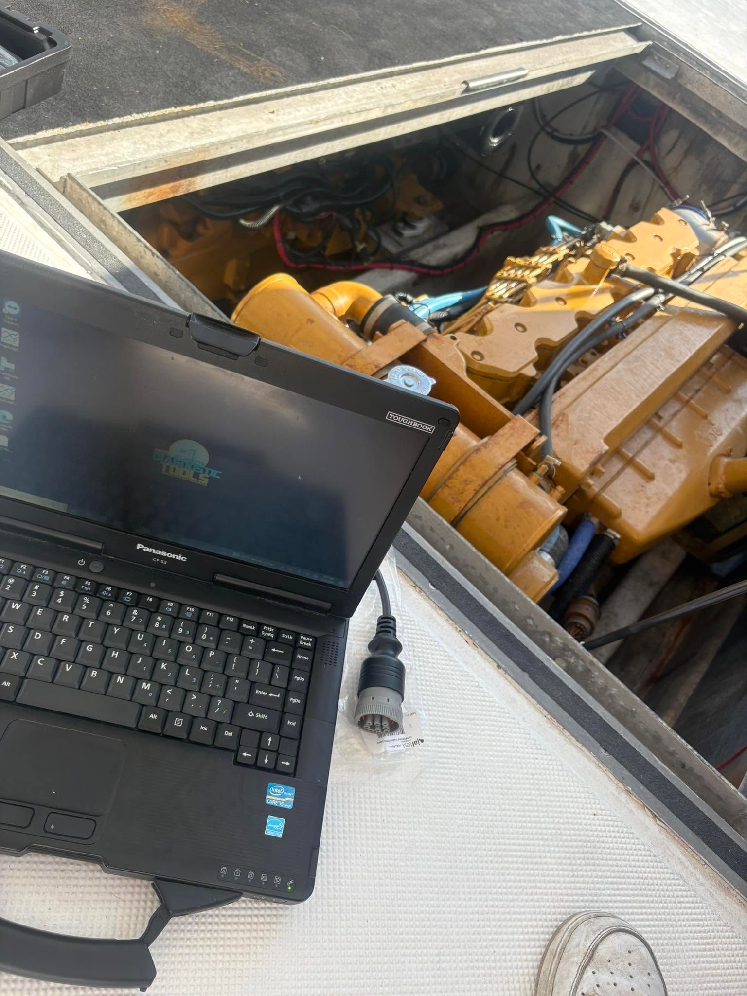 Laptop on a rooftop beside a pile of construction debris and yellow machinery below.