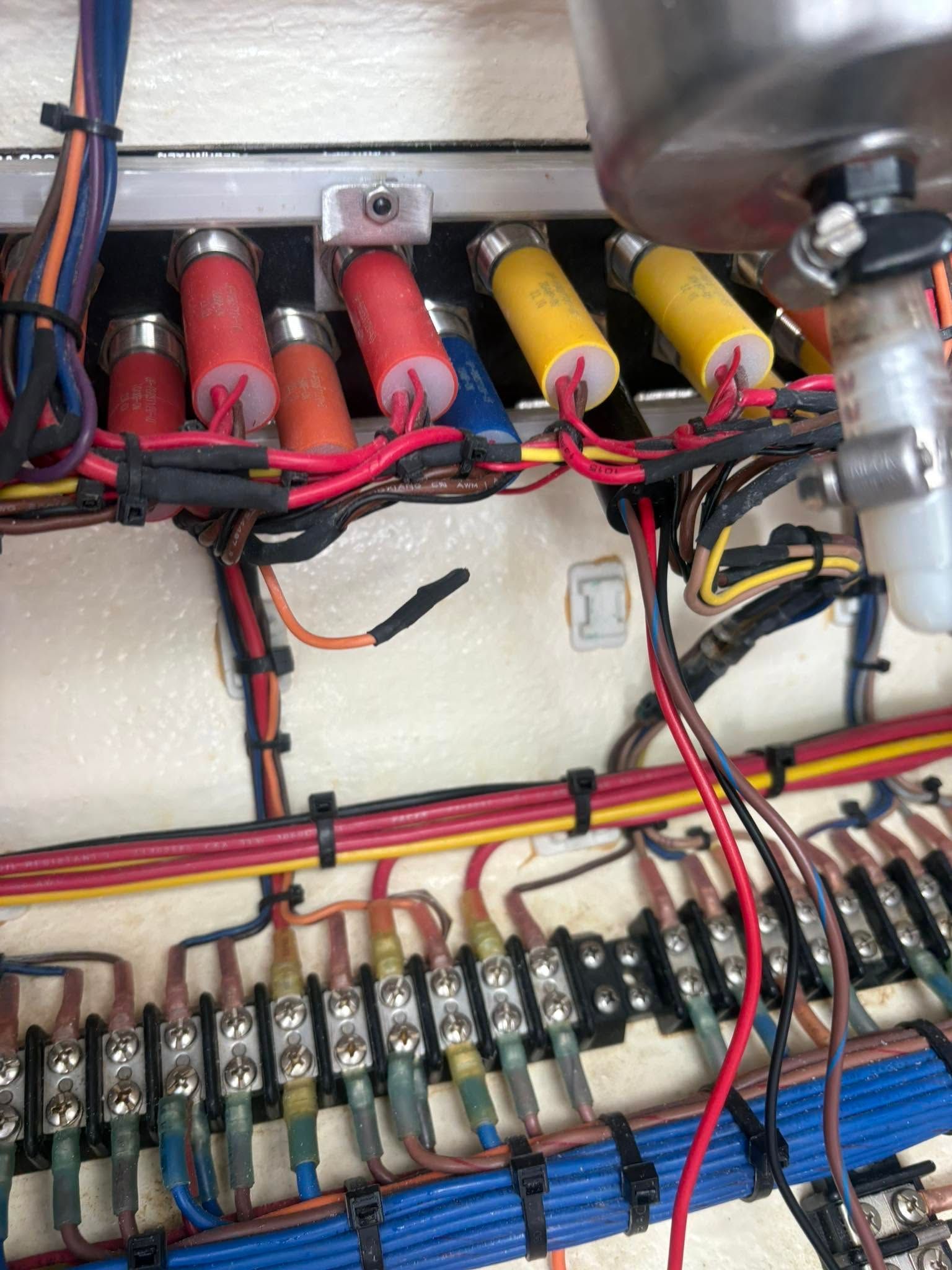 Electrical panel with red and yellow wires connected to terminal blocks and fuse holders inside a cabinet