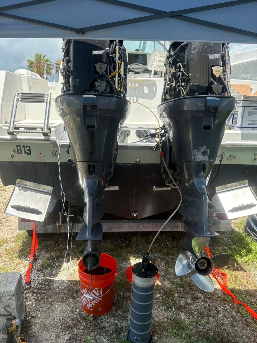 Two fishing rods with reels on a boat, facing a calm canal with homes and docked boats.
