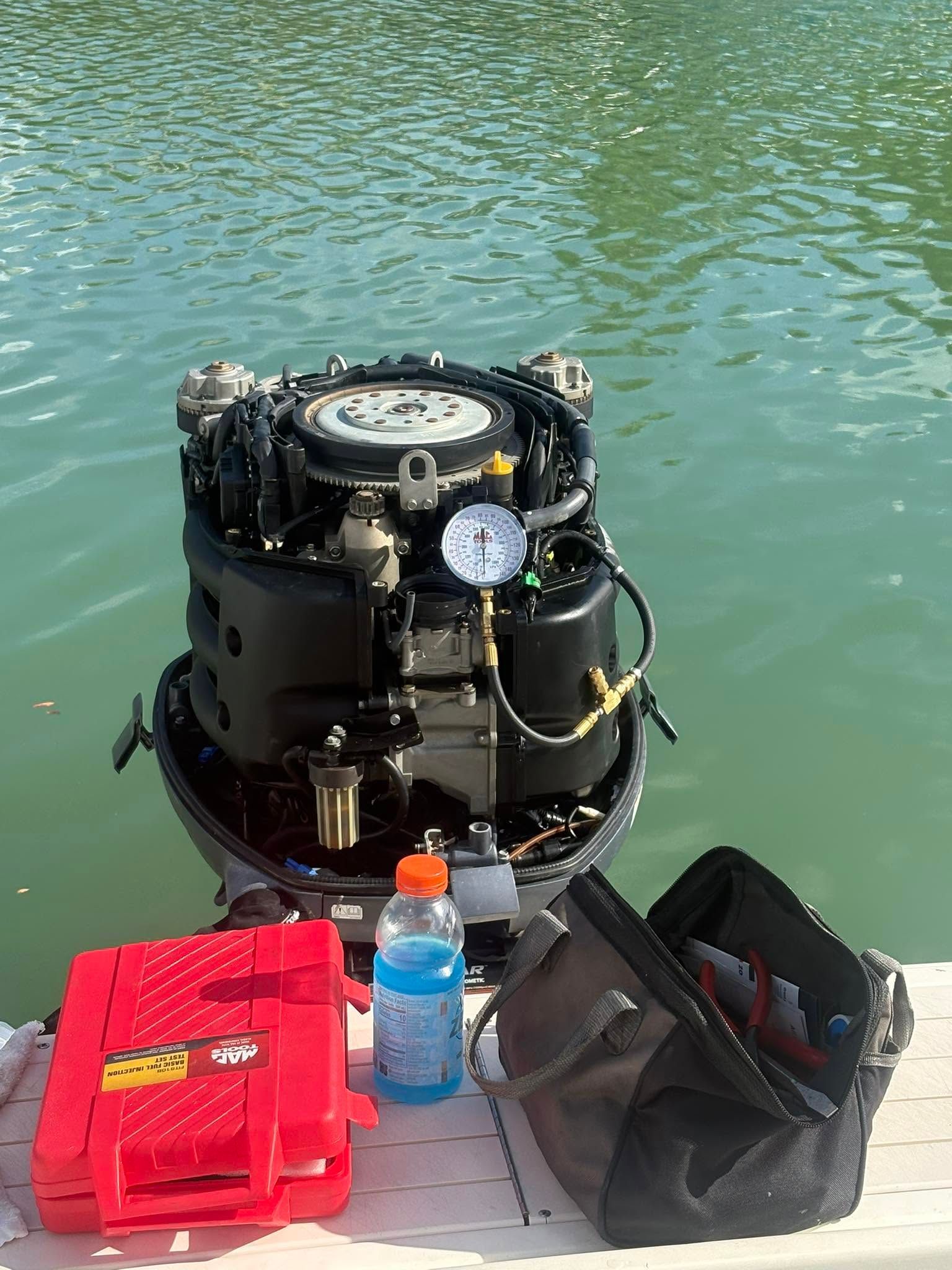 Diving gear and bags on a dock beside green water, with a black scuba tank centered in frame
