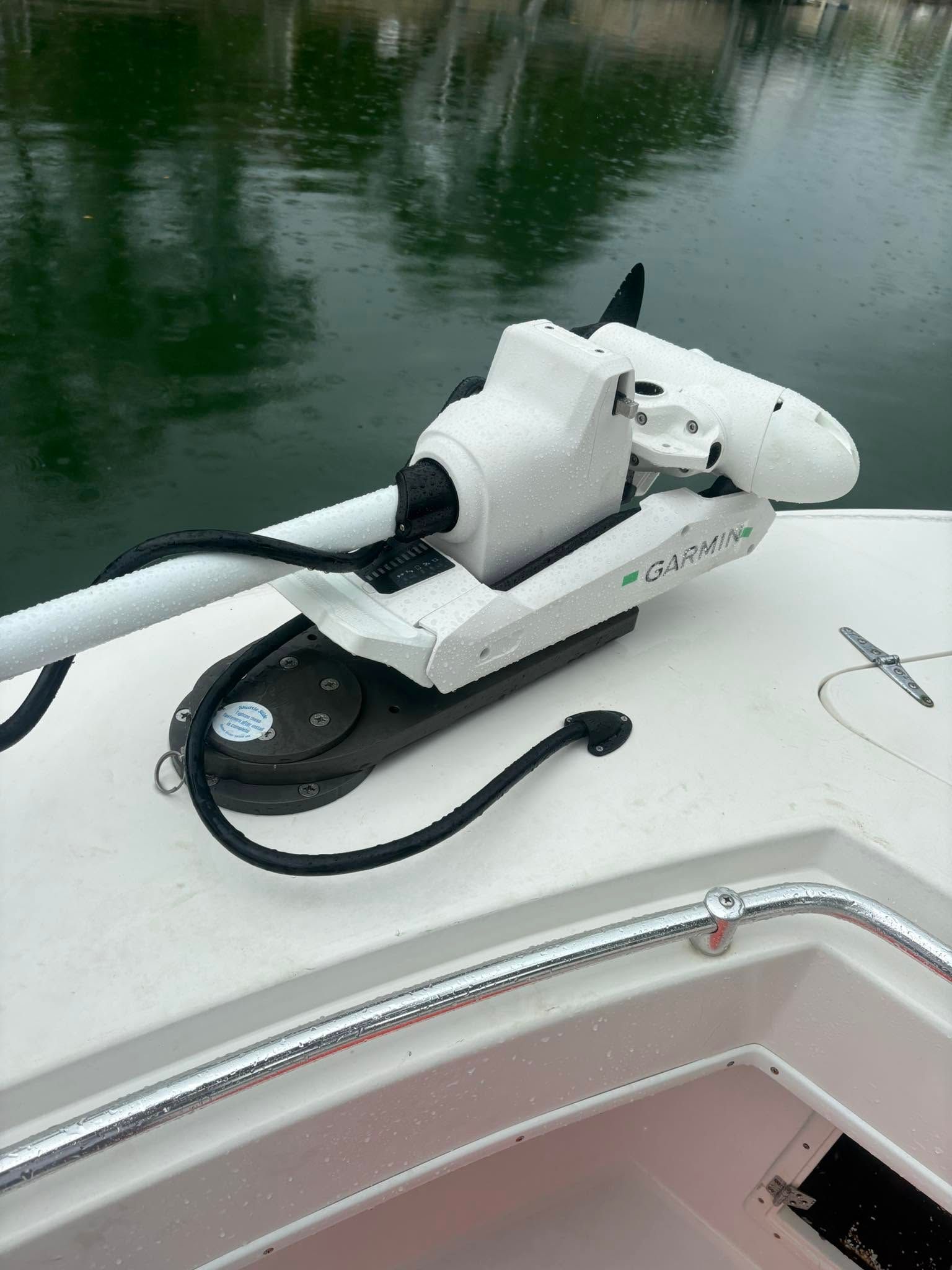 White trolling motor mounted on a boat bow over calm green water.